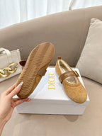 Tan suede flats with textured rubber sole, buckled strap and cream lining visible