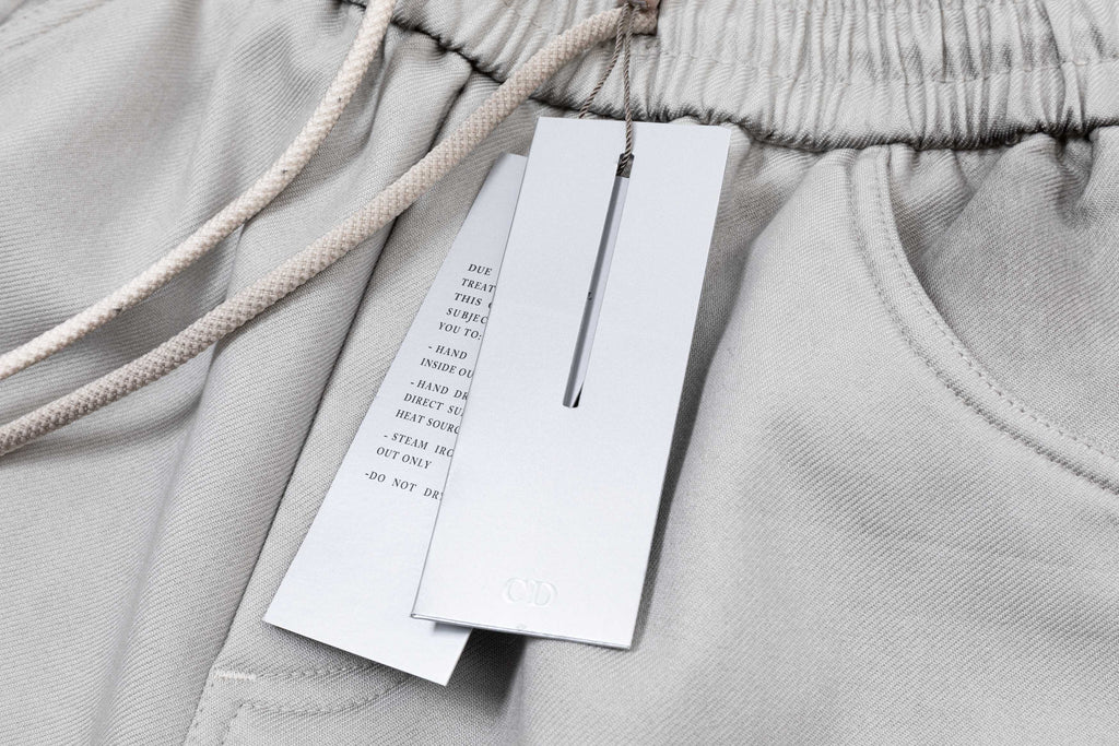 Light gray pants waistband with drawstring and hanging product tags