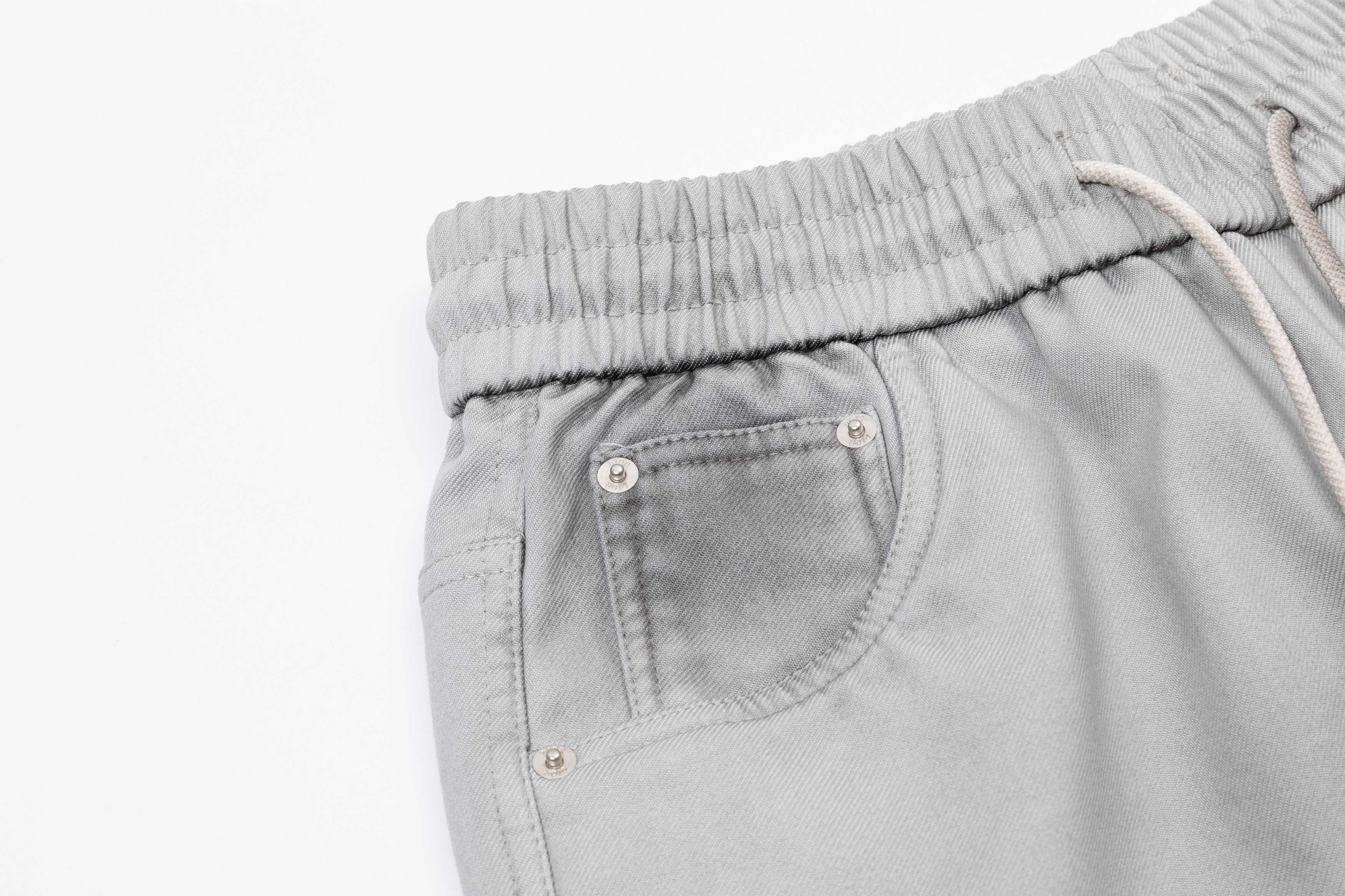 Light gray patch pocket pants with metal snaps and elastic waistband