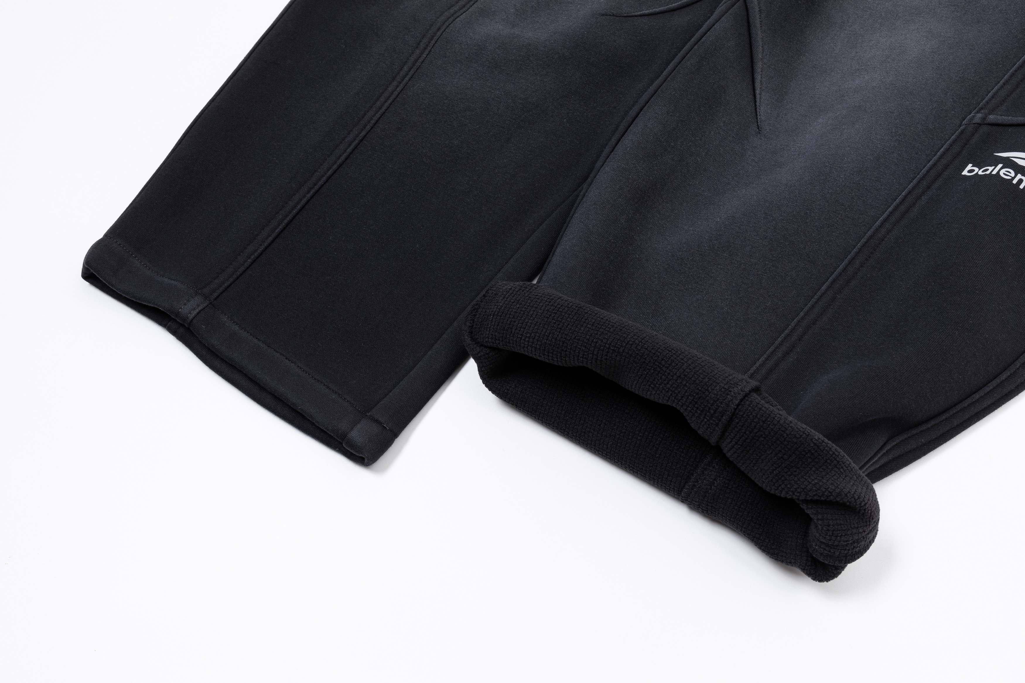 Black pants hem with cuffed cuff detail and draped drawstring