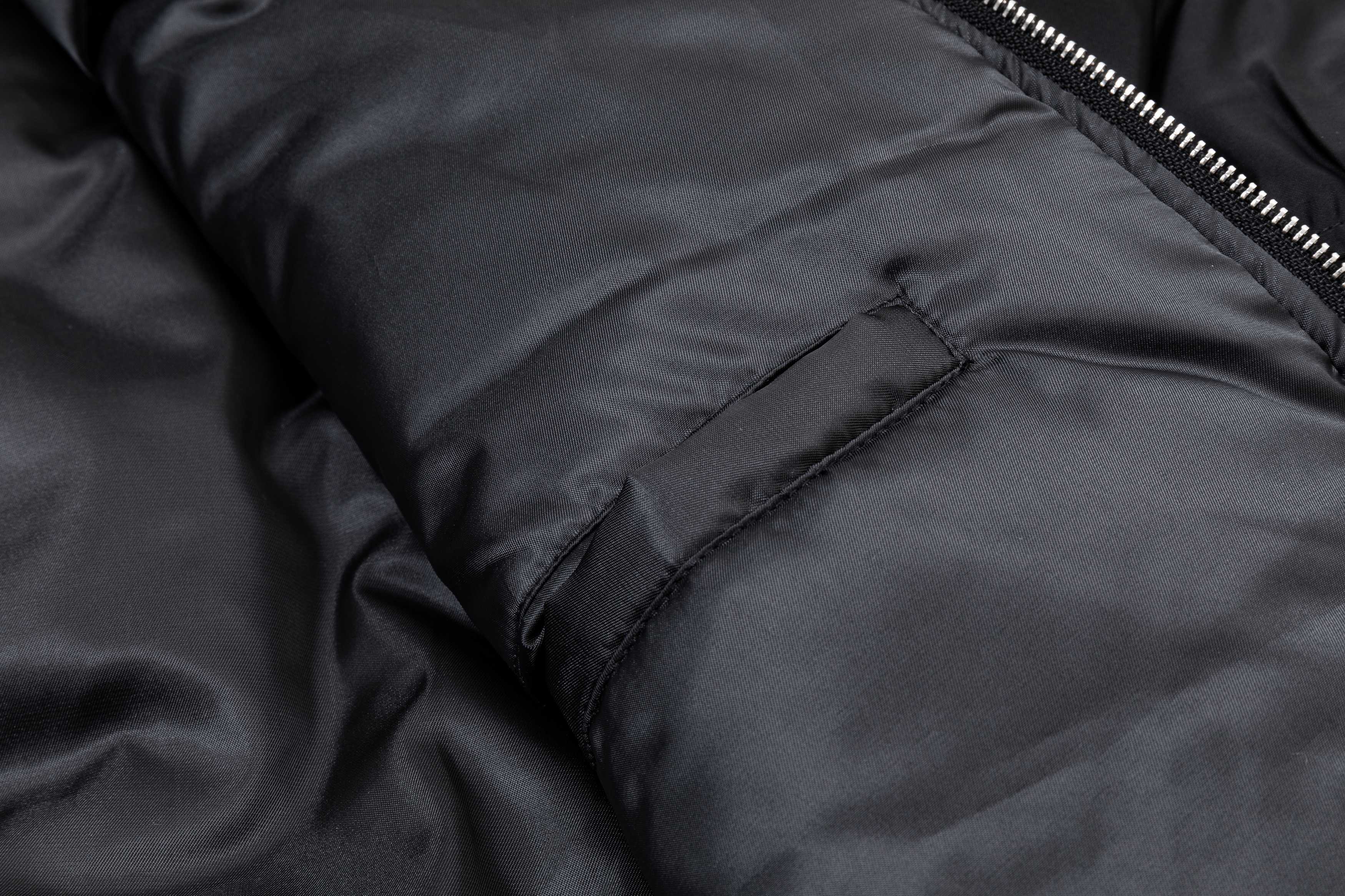 Black bomber jacket arm section with seam stitching and pocket flap detail