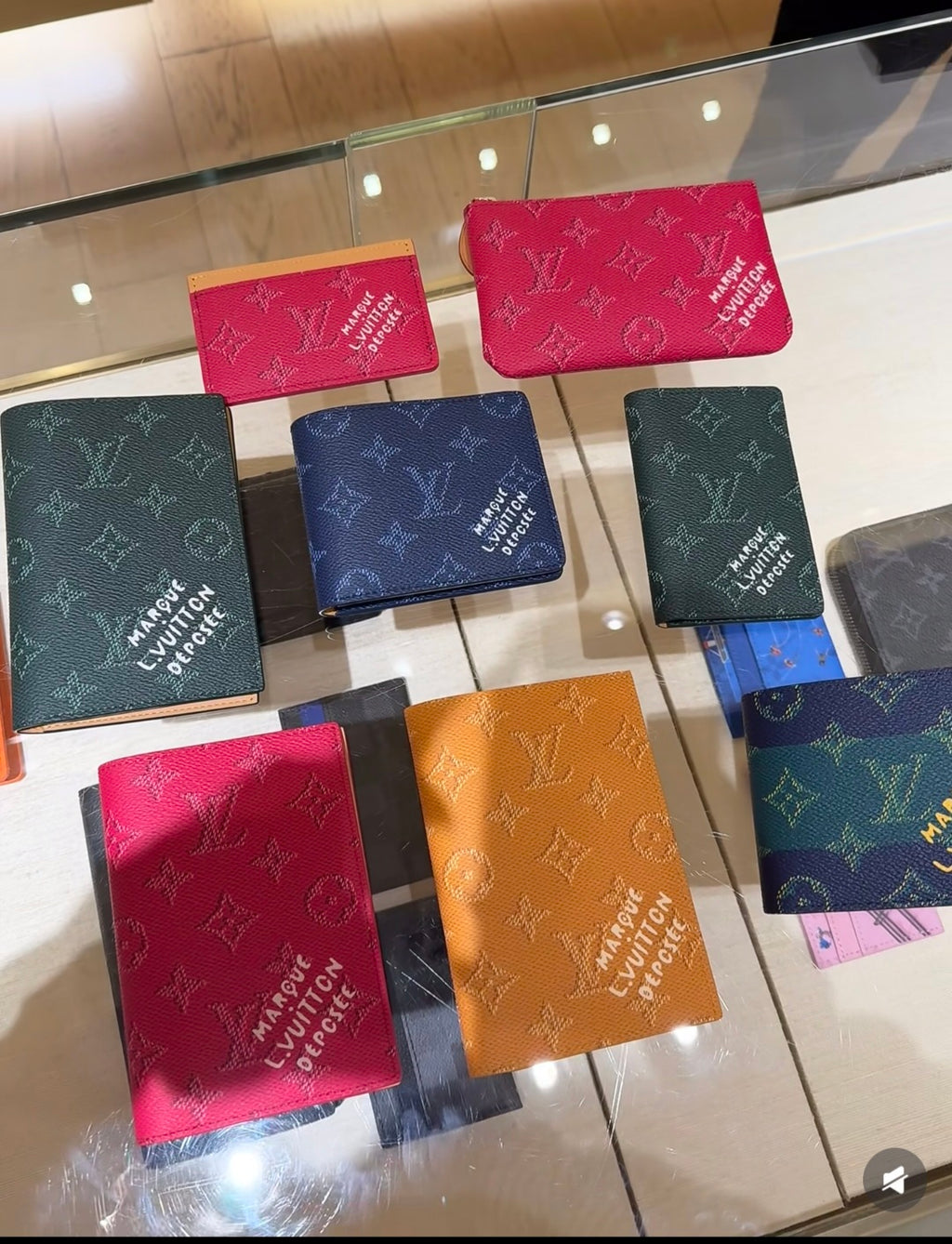 Assorted Louis Vuitton small pouches with monogram print in multiple colors on display