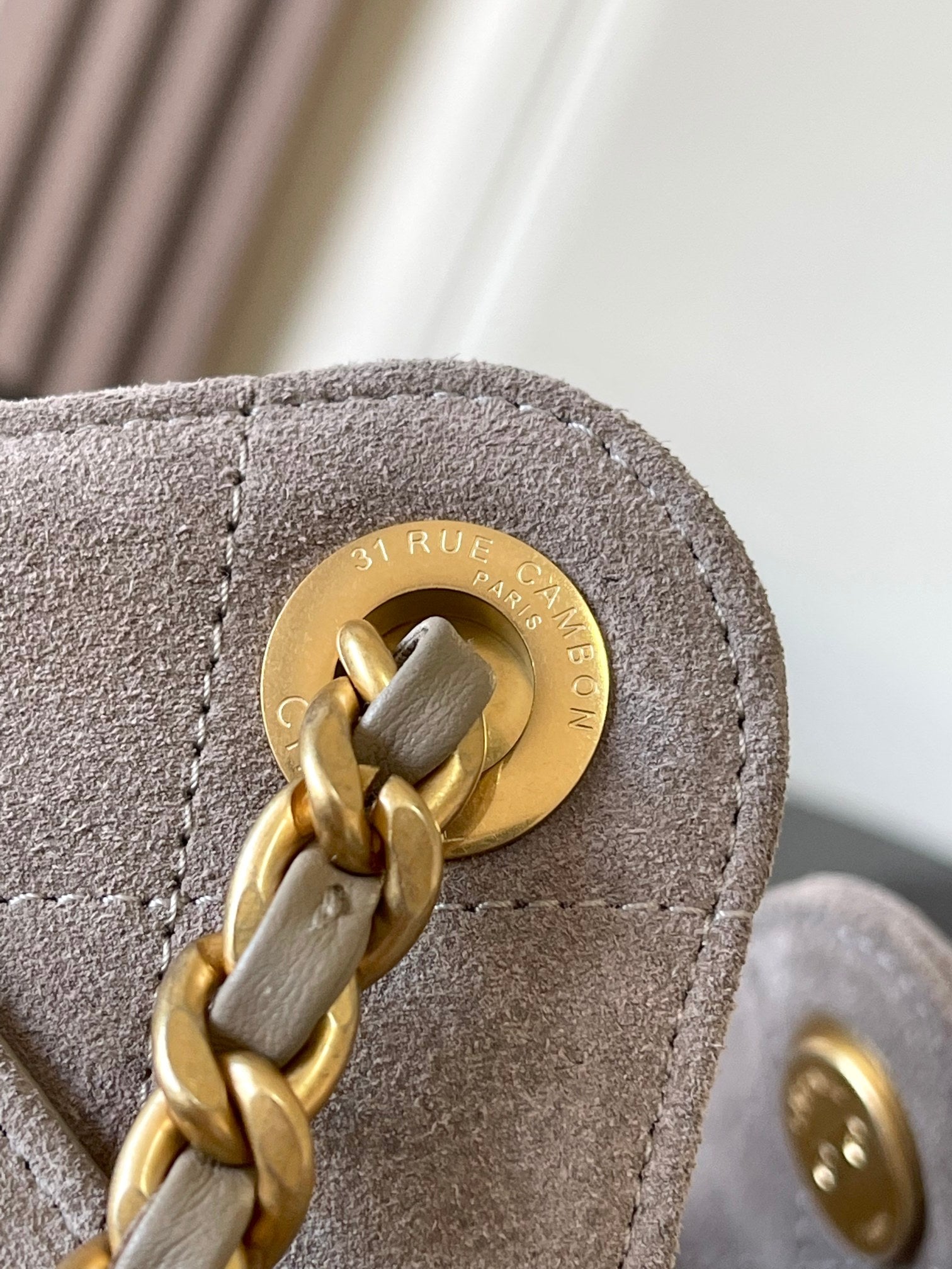 Chanel chain-link clasp and round logo on light gray suede bag