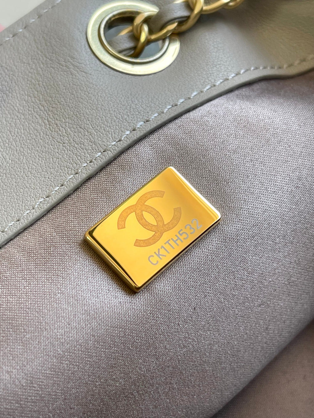 Chanel gold logo charm on light gray bag with gold chain link