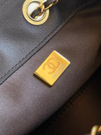 Dark brown bag exterior with gold logo plate and ring hardware
