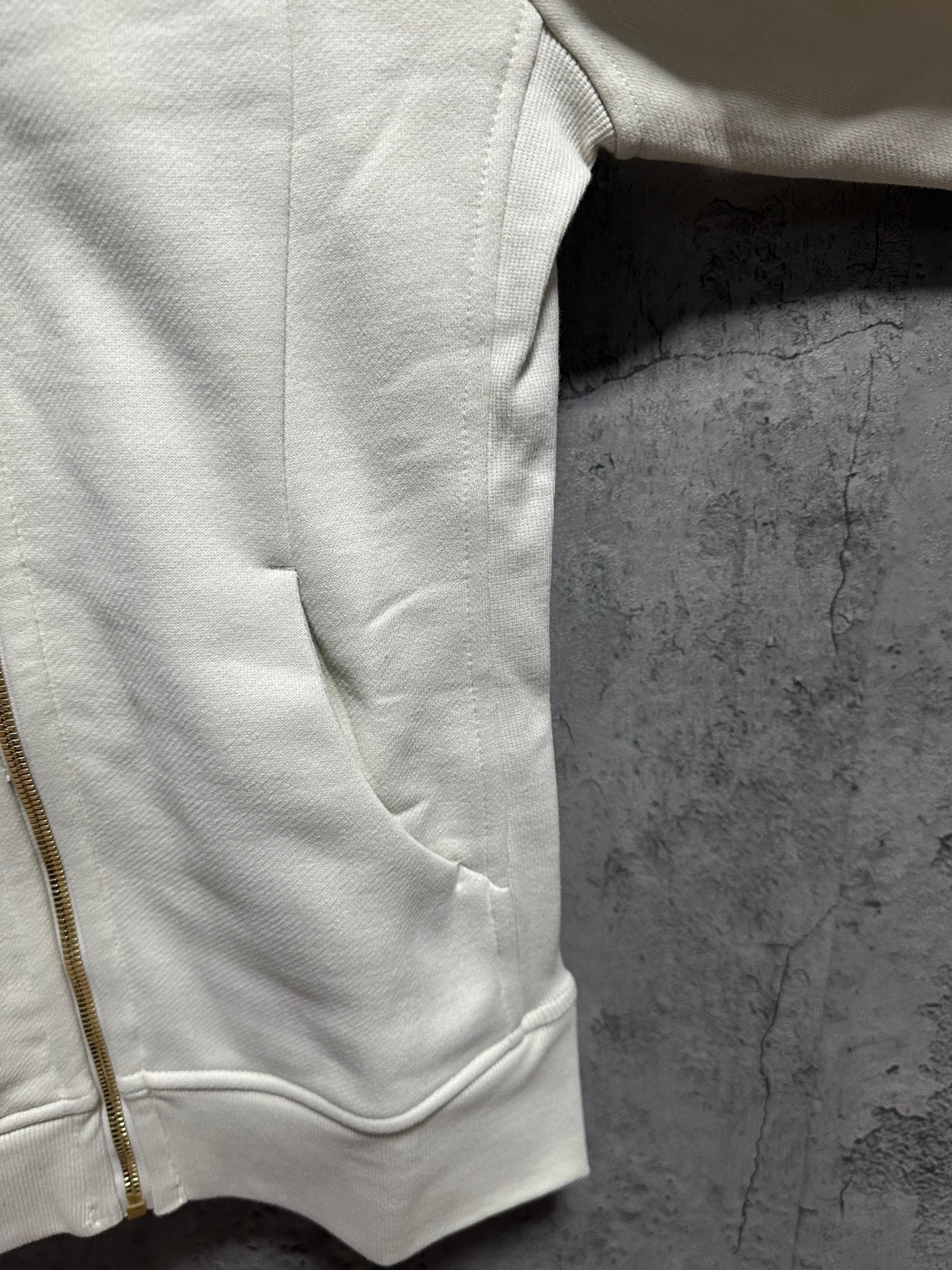 Cream hoodie sleeve and hem, showing side zipper seam