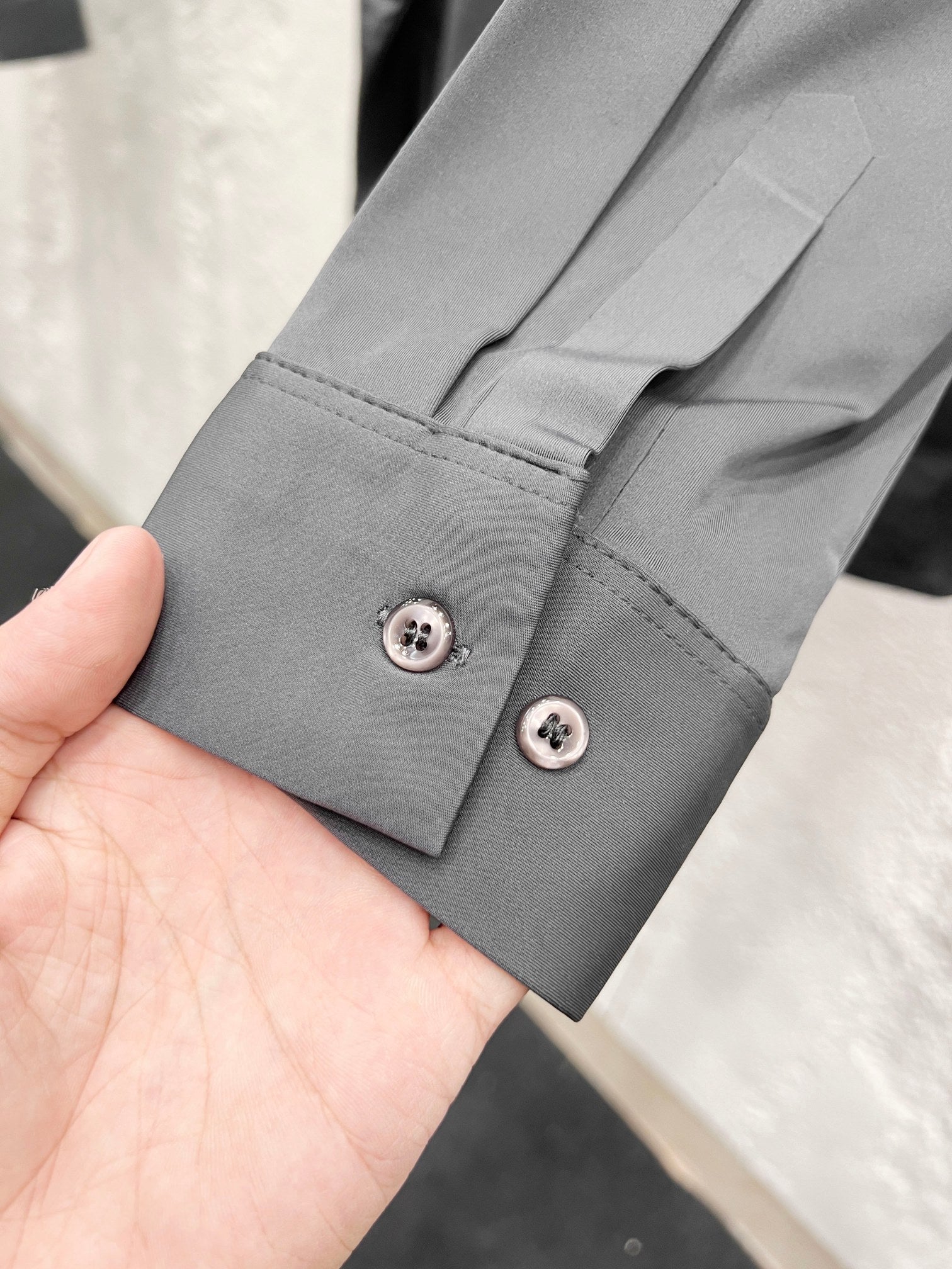 Versace shirt cuff with two button closures, grey fabric.