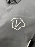 Versace chest crest patch with V emblem on grey button-up shirt.