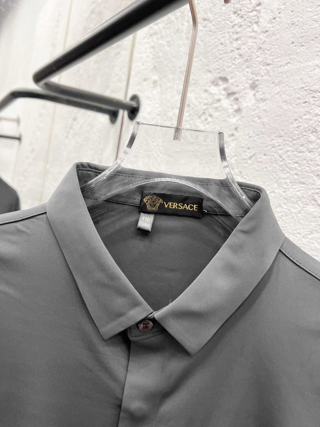 Versace dress shirt collar with inner label, grey button-up on hanger.