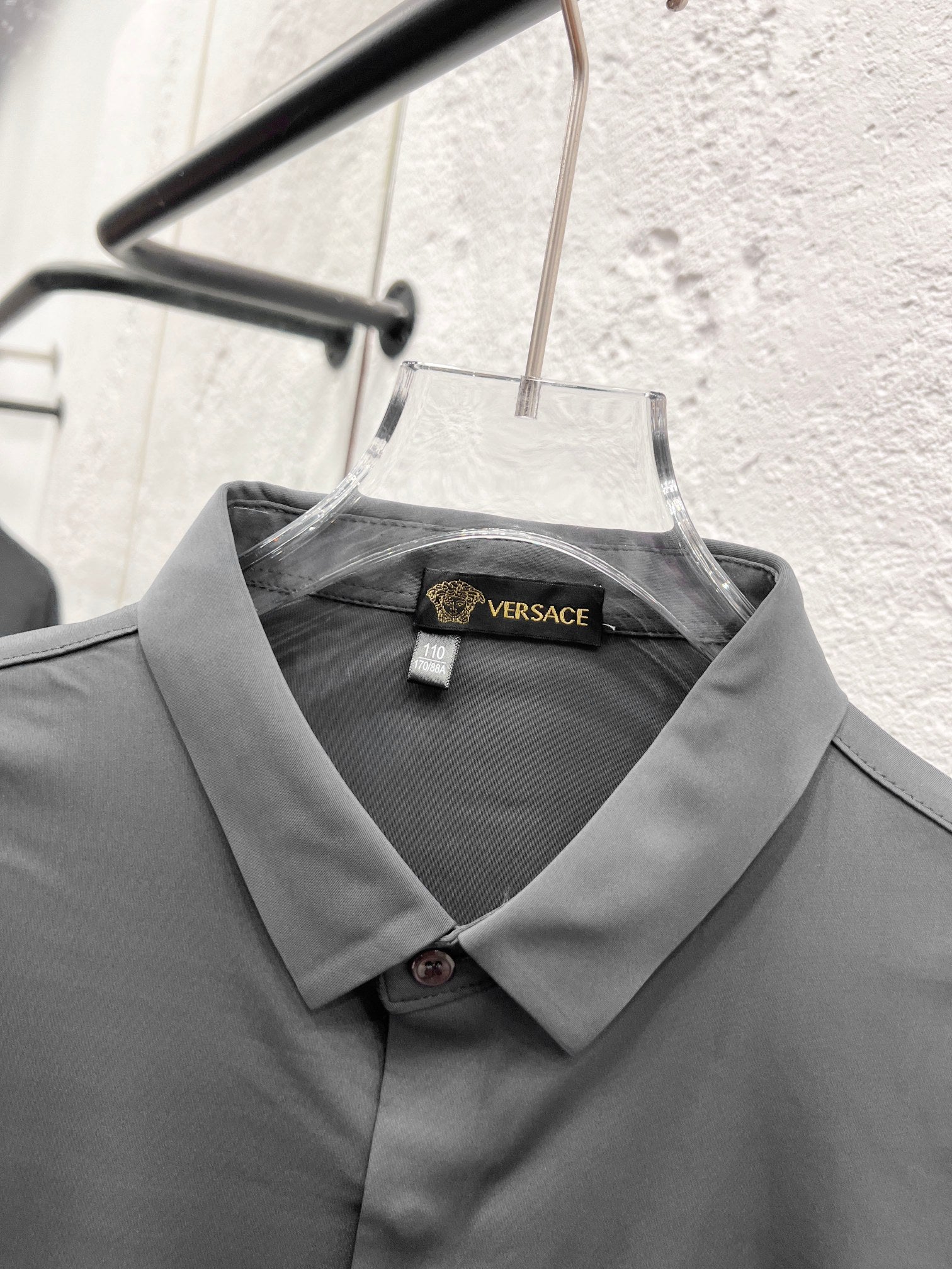 Versace dress shirt collar with inner label, grey button-up on hanger.