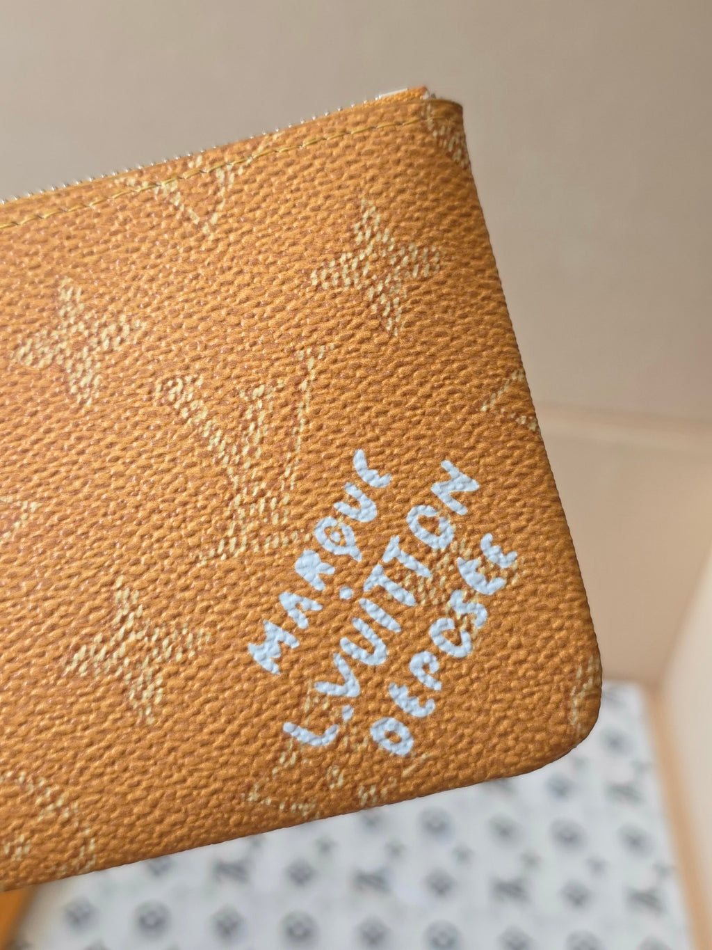Louis Vuitton monogram zip pouch close-up of embossed logo and blue stamped text