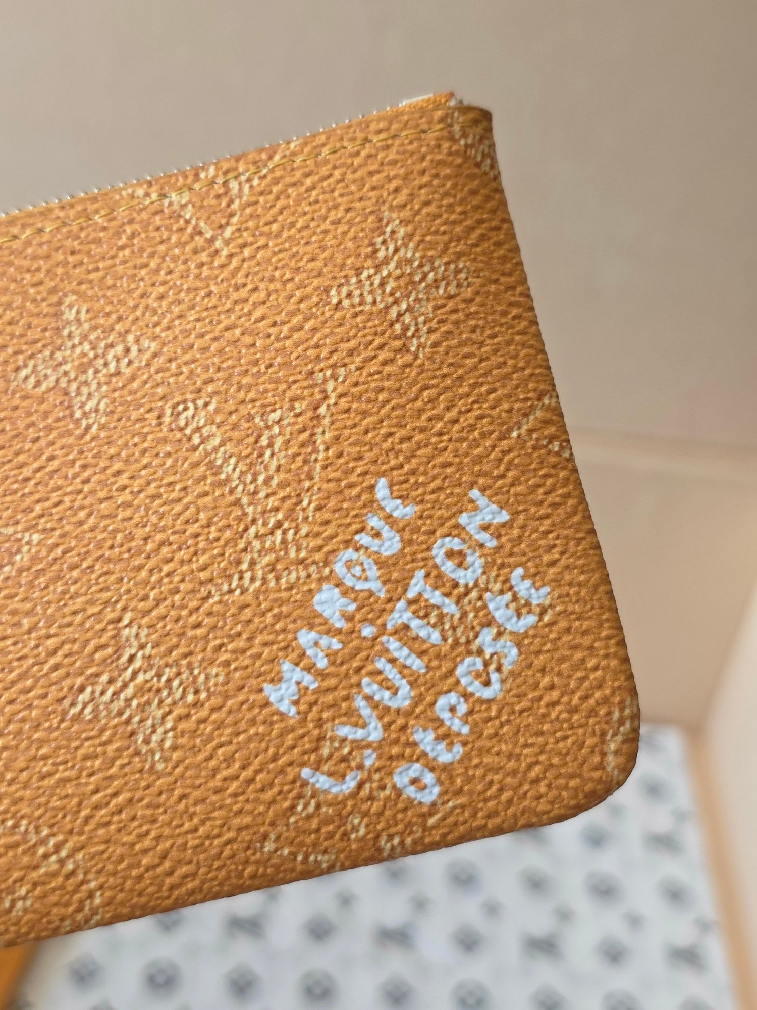 Louis Vuitton monogram zip pouch close-up of embossed logo and blue stamped text