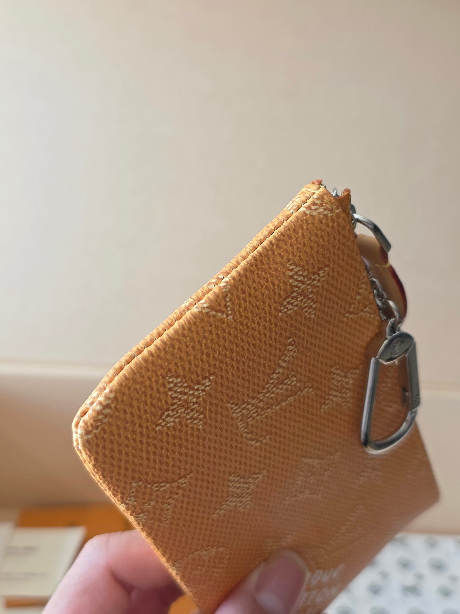 Louis Vuitton monogram zip pouch side view with silver clasp and tan-brown canvas