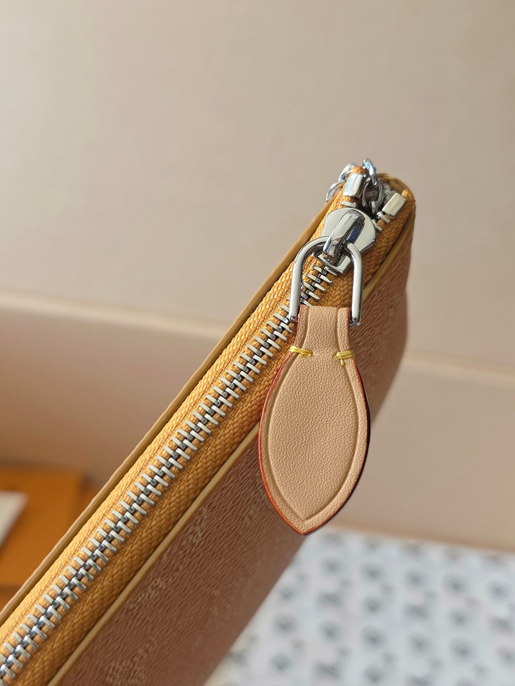 Small Louis Vuitton monogram bag close-up of zipper and leather pull tab