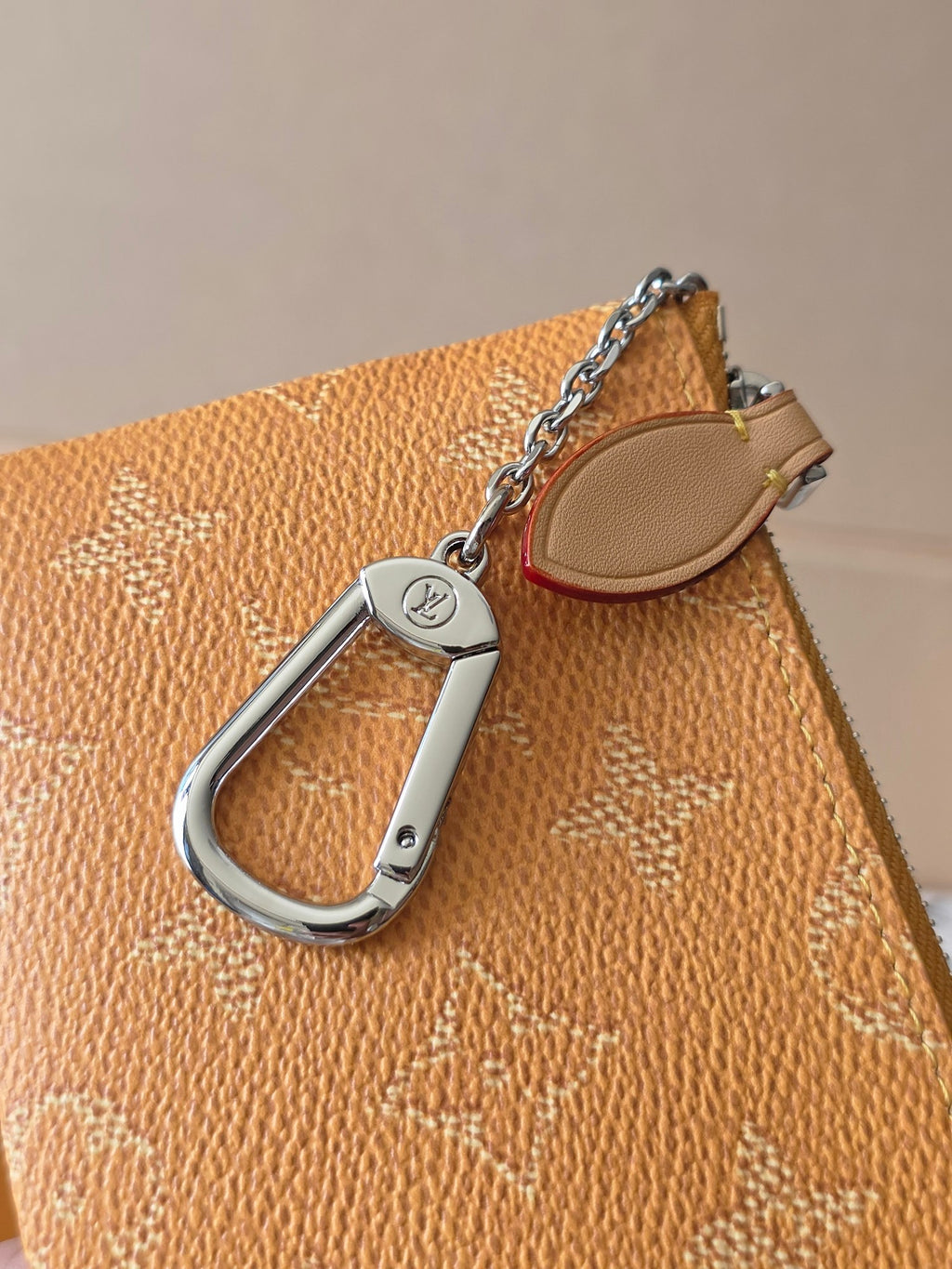 Louis Vuitton monogram zip pouch corner detail with silver D-ring and tan leather trim
