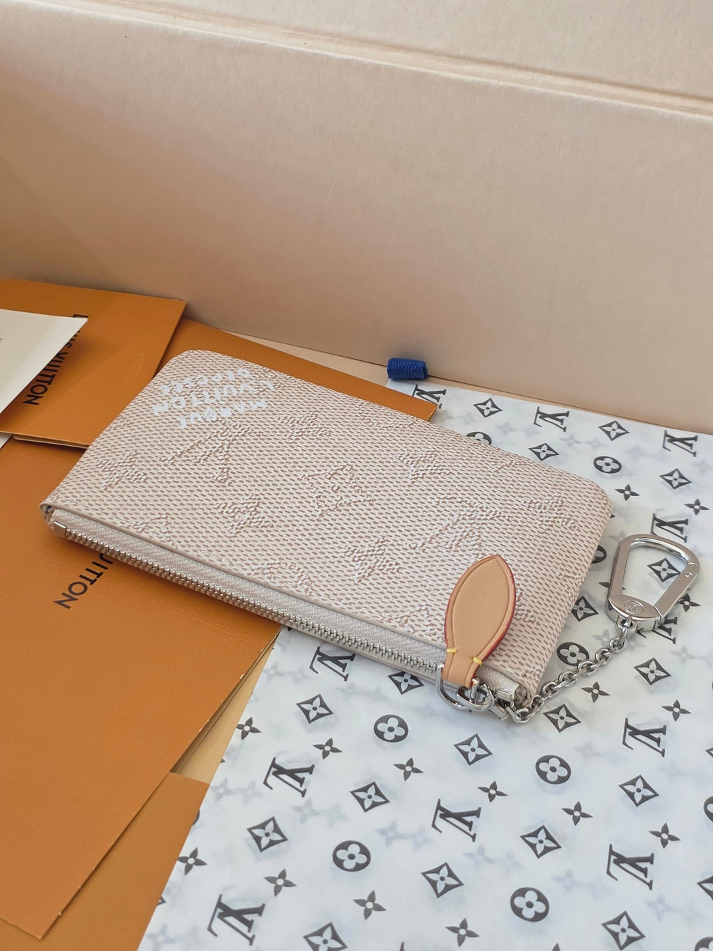Small zip pouch with tan leather top pull tab and silver chain strap, monogram