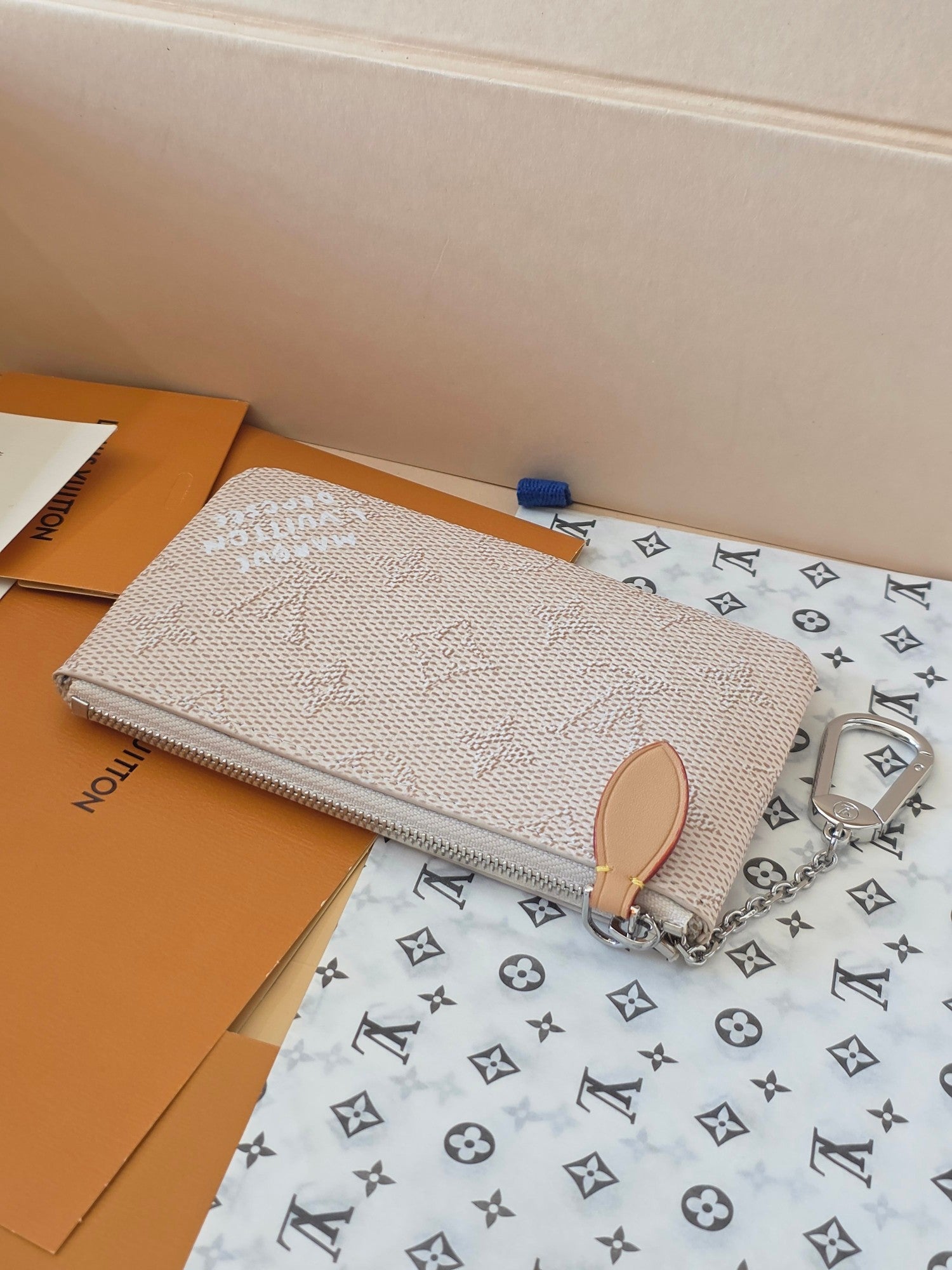 Small zip pouch with tan leather top pull tab and silver chain strap, monogram
