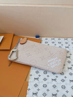 Small zip pouch with tan leather handle and silver keychain-style D-ring, monogram