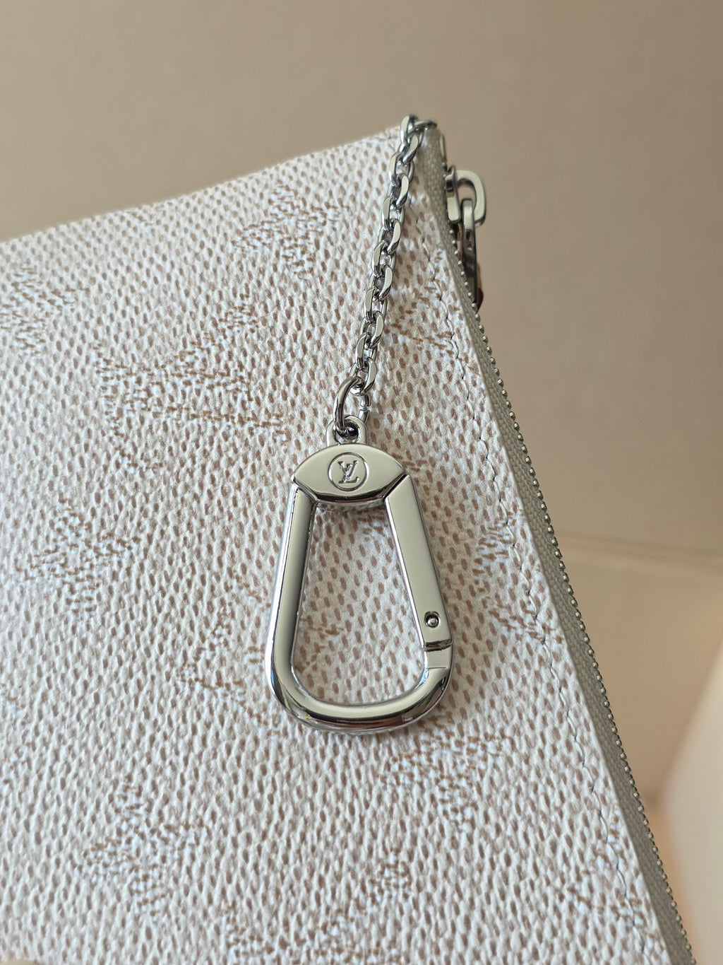 Small zip pouch top view with silver chain and snap hook on textured canvas