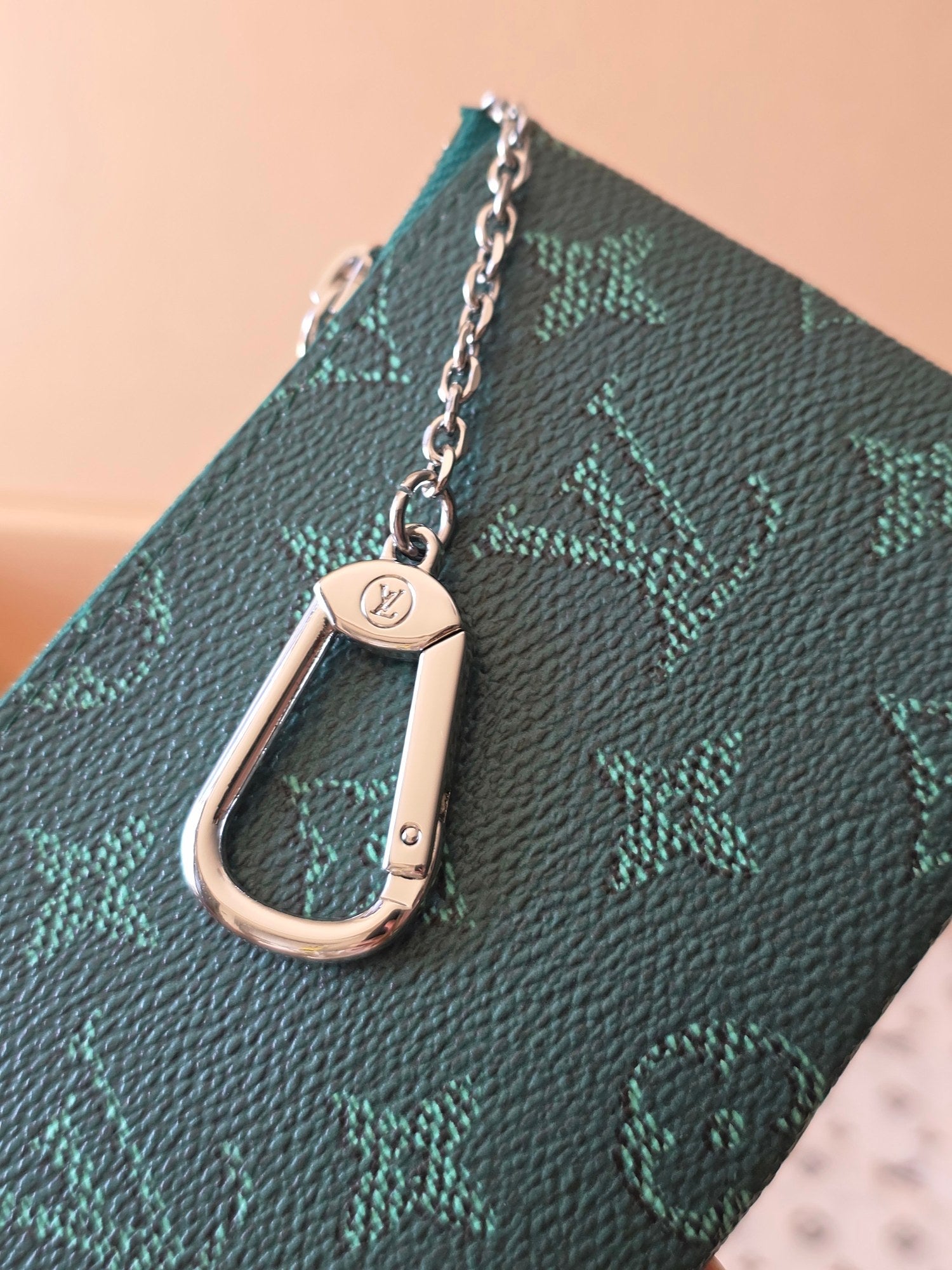 Louis Vuitton small bag close-up: teal monogram canvas with silver clasp and chain