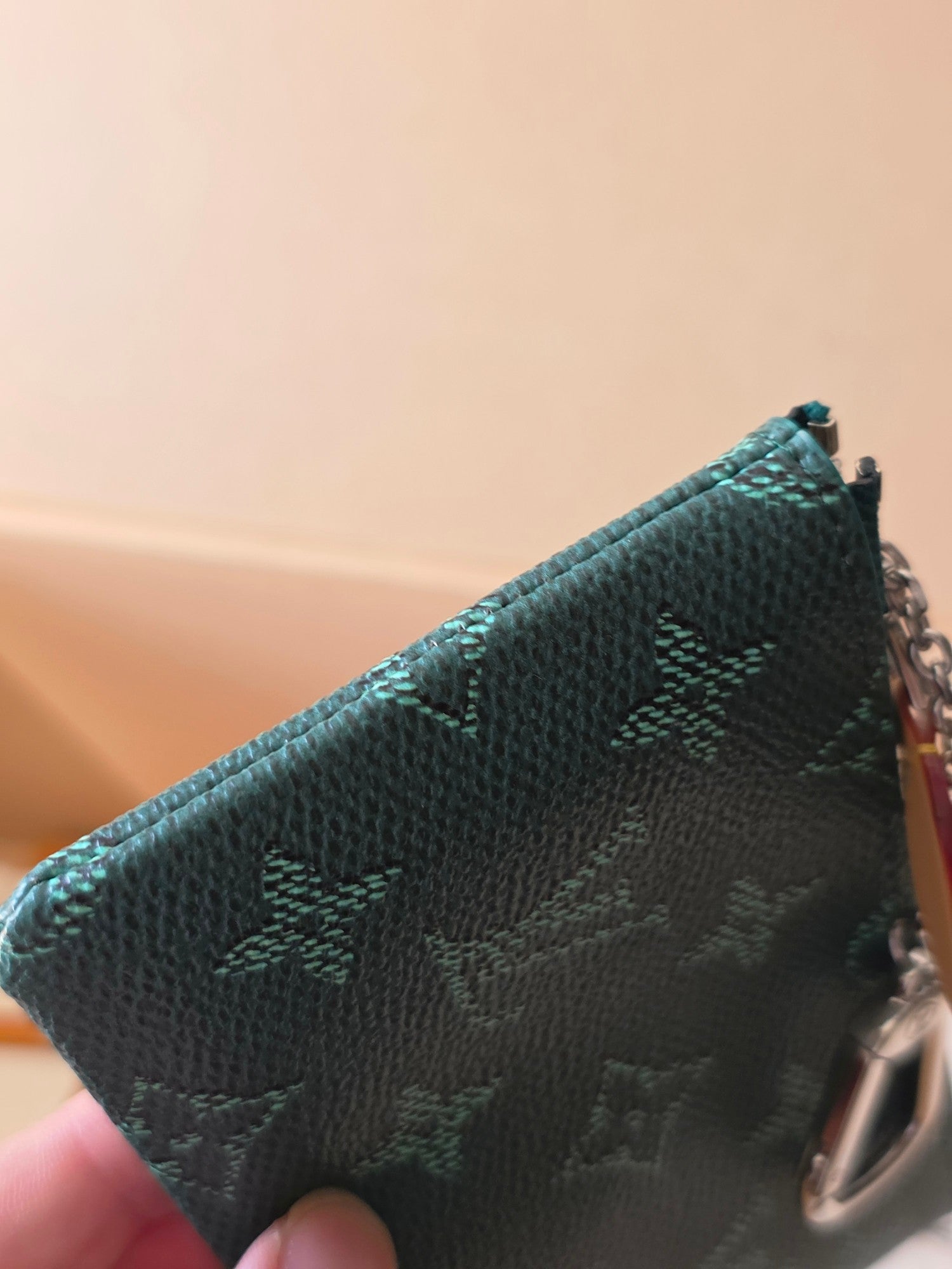 Louis Vuitton small bag corner close-up with teal monogram canvas and metal chain ring