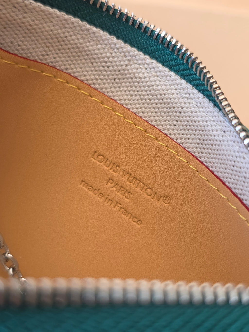 Beige interior lining with embossed Louis Vuitton branding under the zipper