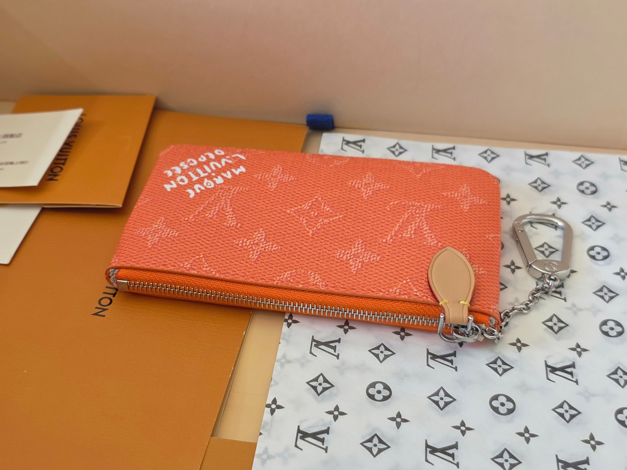 Orange Louis Vuitton monogram pouch bag with zipper closure and round pull tab.