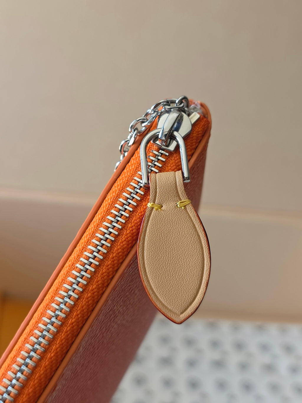 Orange monogram pouch with silver zipper and beige leather tab