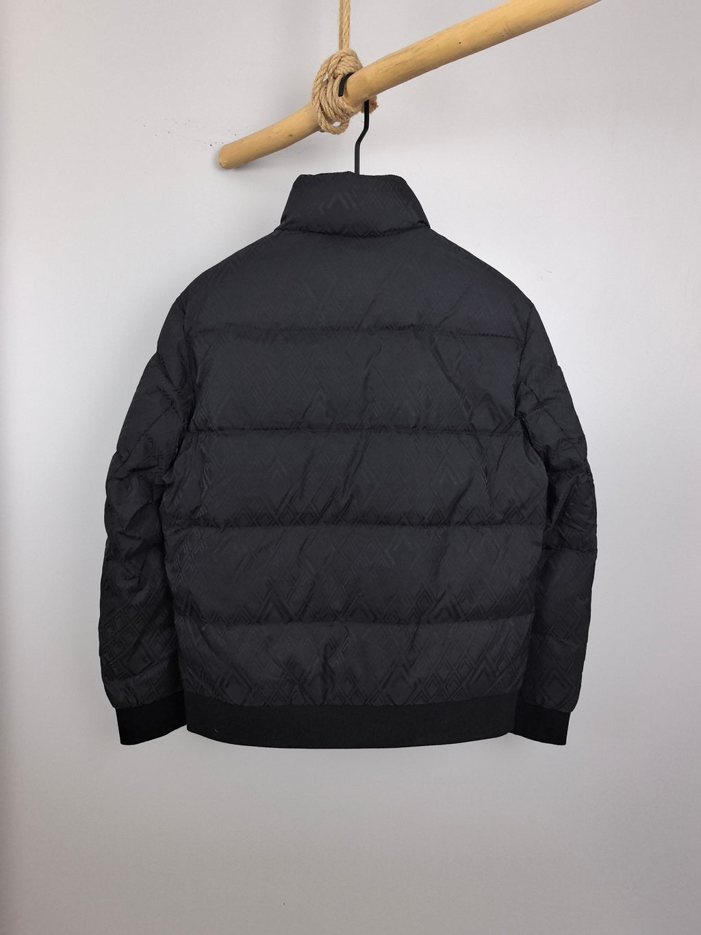 Black long-sleeve puffer jacket, back view, full zipper and quilted panels