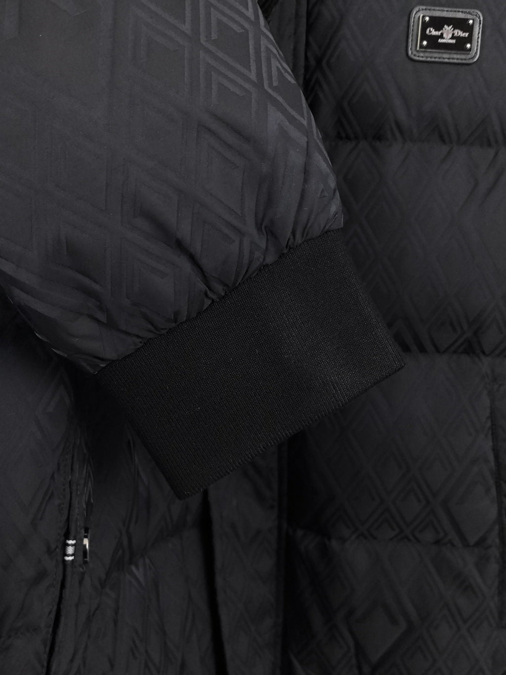 Black puffer jacket fabric detail with ribbed cuff and logo label