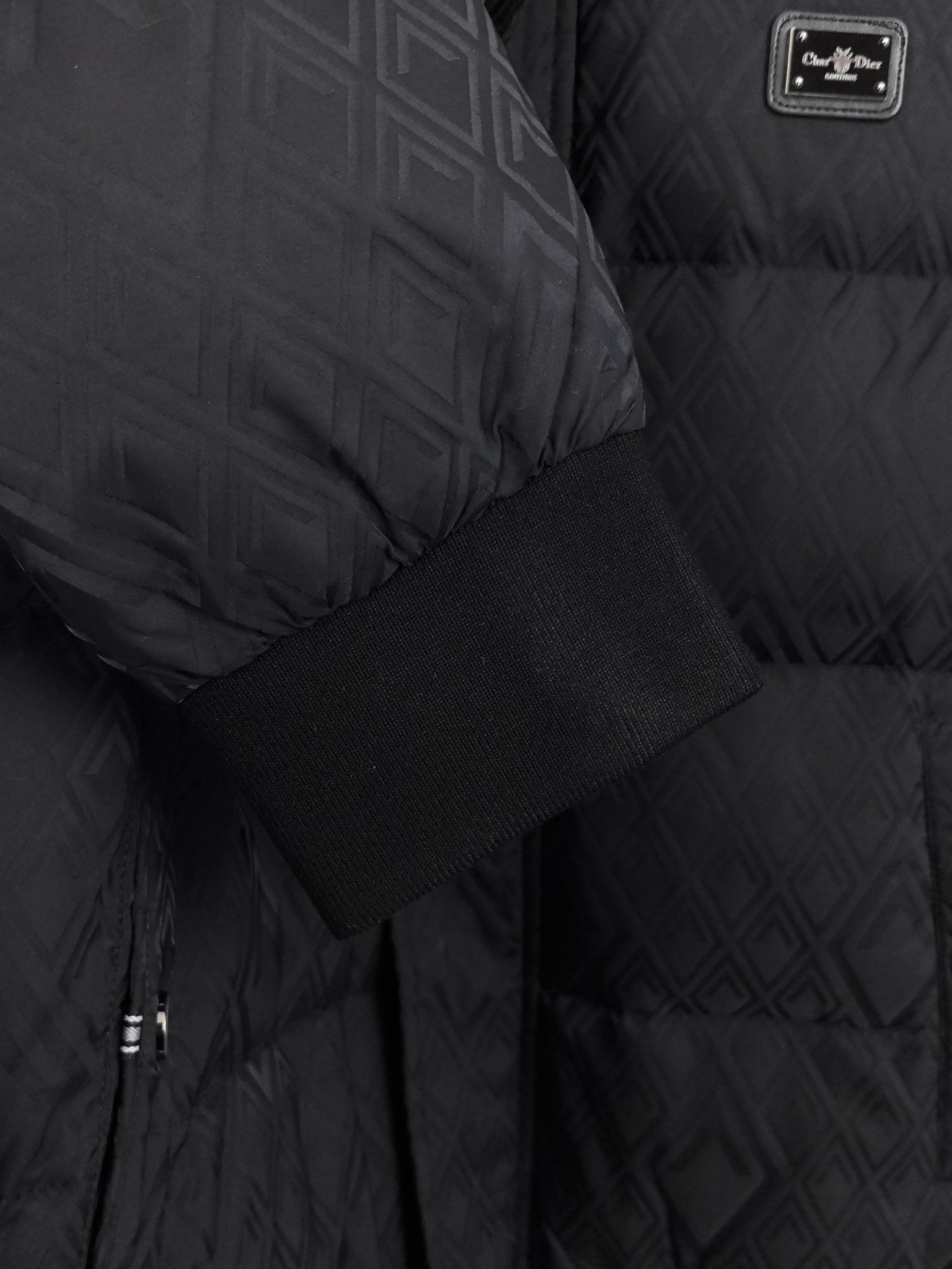 Black puffer jacket fabric detail with ribbed cuff and logo label