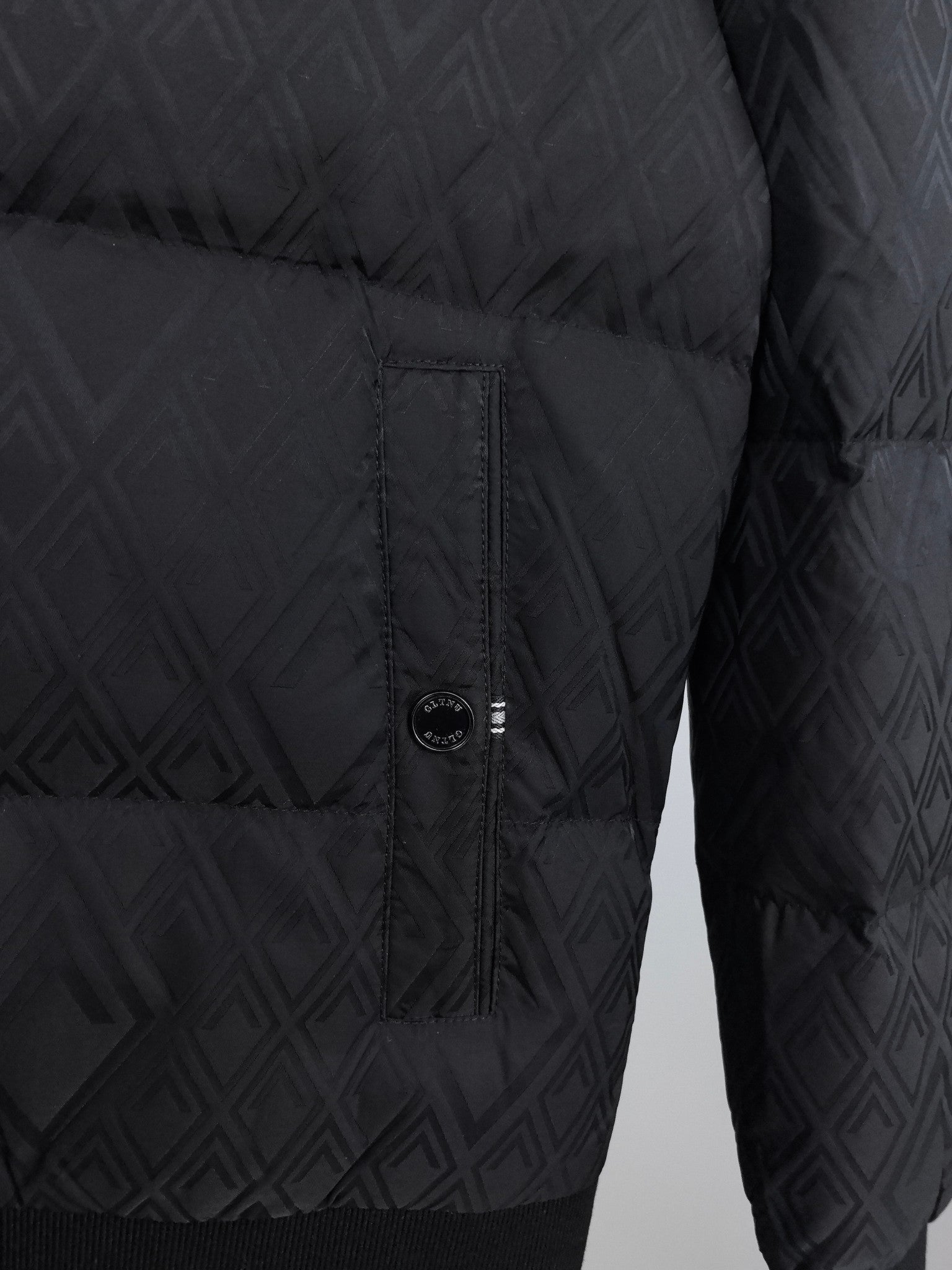 Black puffer jacket side view with center front zipper and logo emblem
