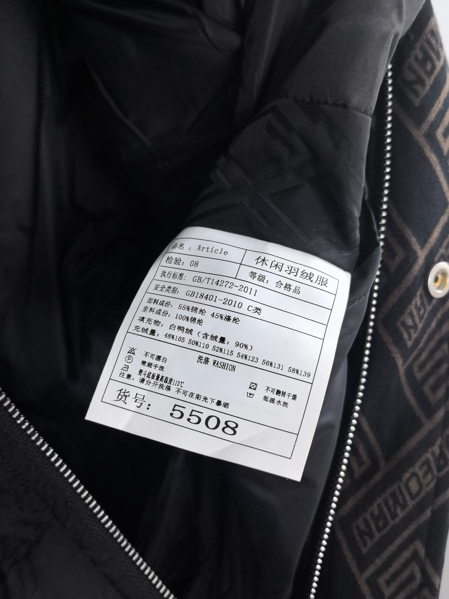 Black puffer jacket close-up of interior care label with size and material info