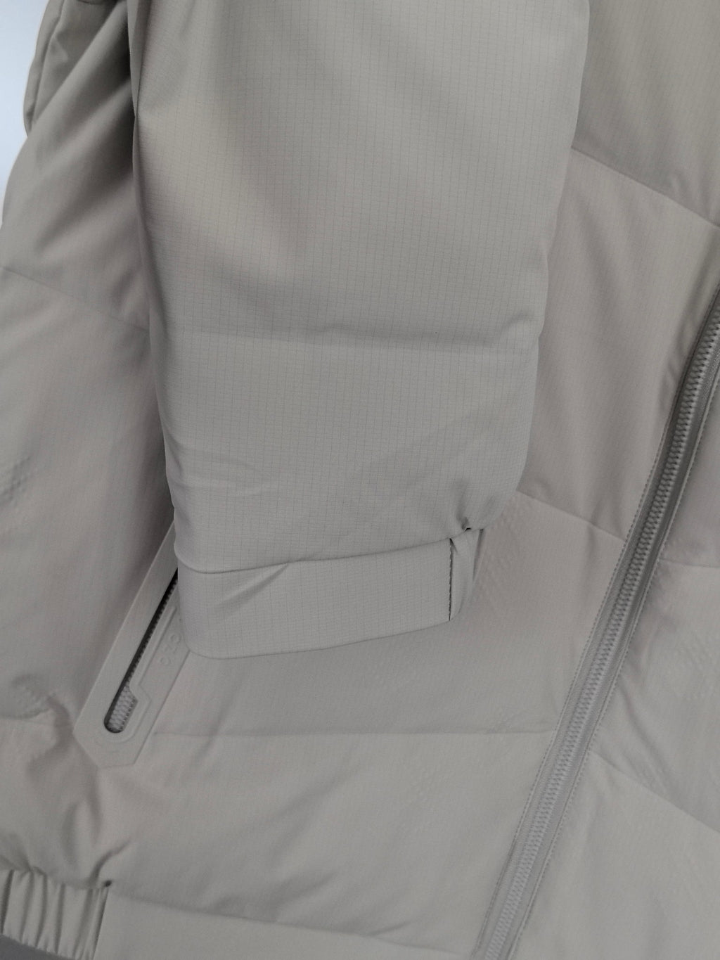 Light beige padded jacket side with zip pocket and stitched seam