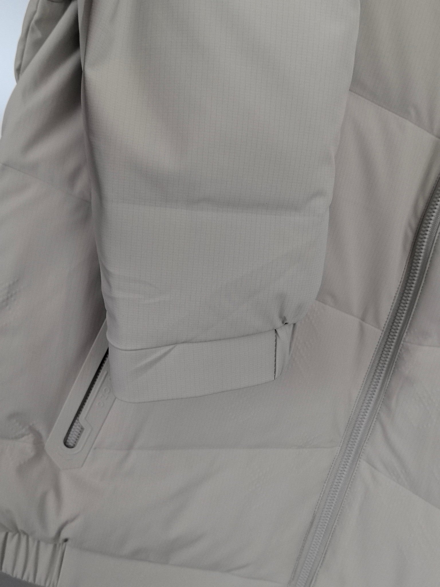 Light beige padded jacket side with zip pocket and stitched seam