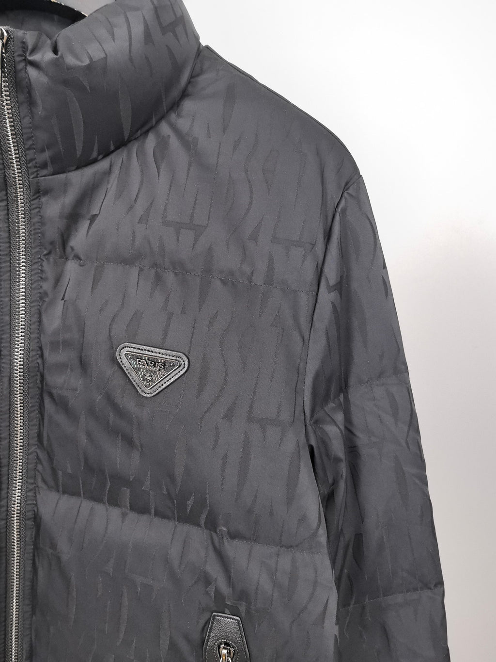 Prada dark puffer jacket close-up with logo patch and side seam zipper