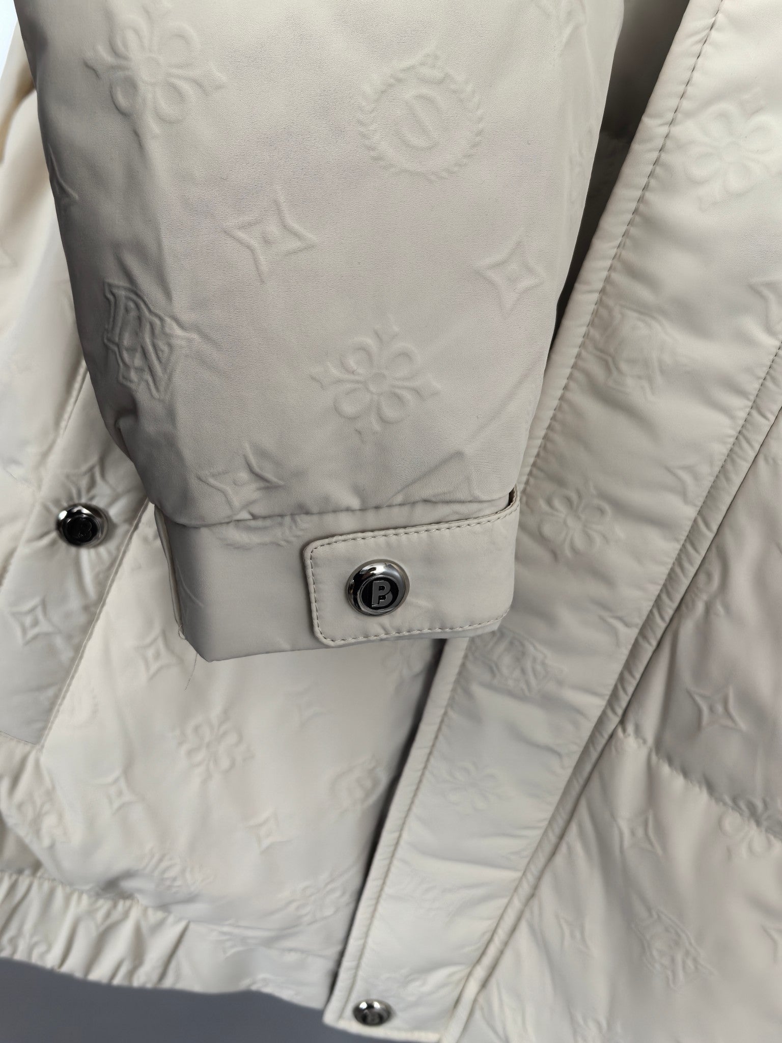 Burberry puffer jacket cuff area, cream with snap buttons and logo tab patch