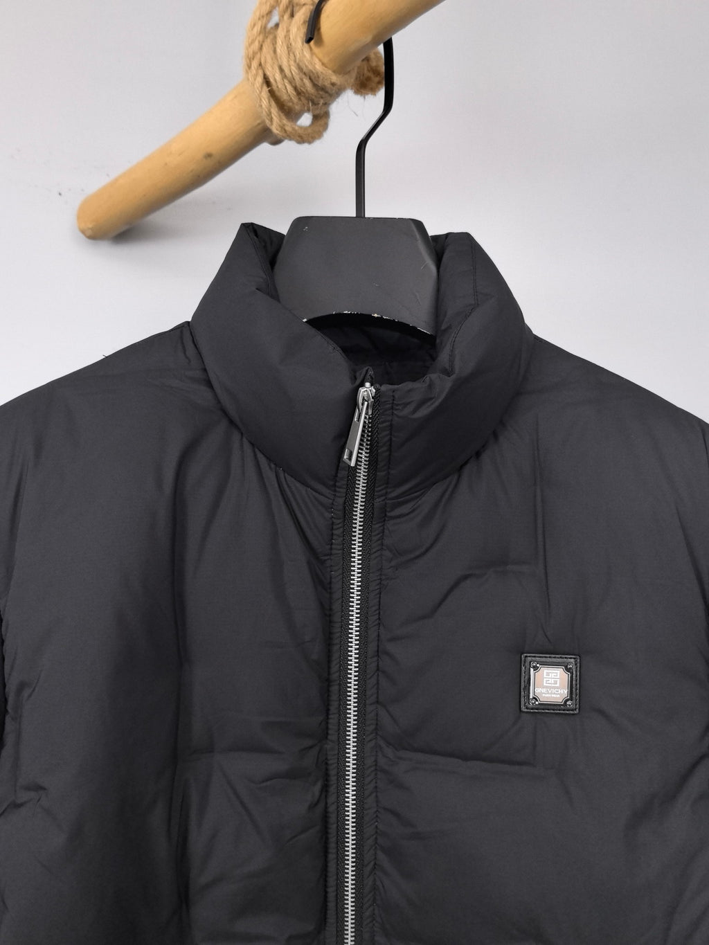 Black puffer jacket front with stand collar, full zipper, and chest logo patch
