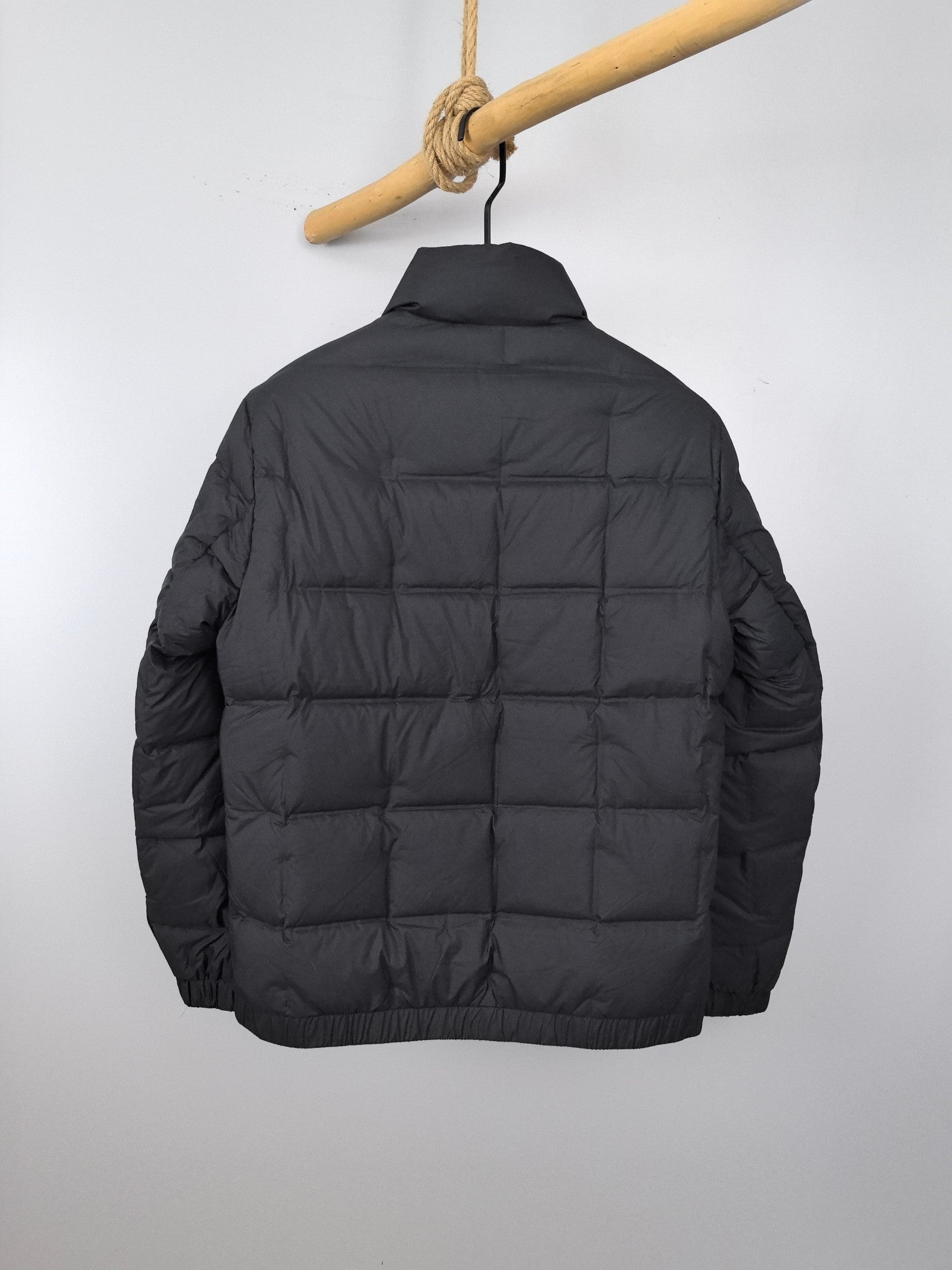 Black puffer jacket back view with padded quilted panels and full zipper