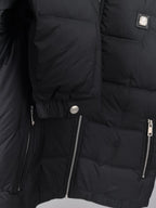 Black puffer jacket close-up of side zip pocket and logo pull tab