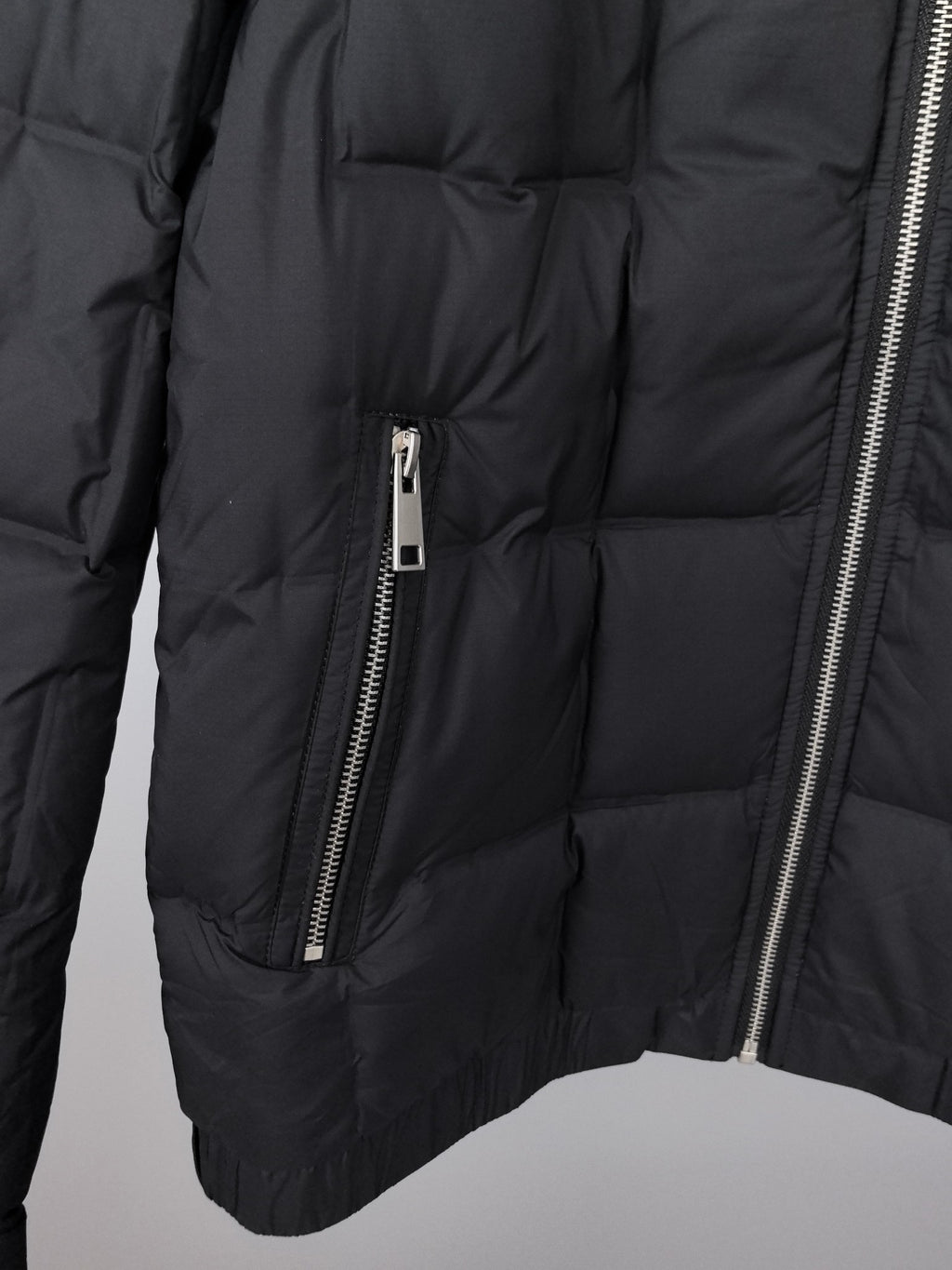 Black puffer jacket close-up showing center zip and quilted padded panels