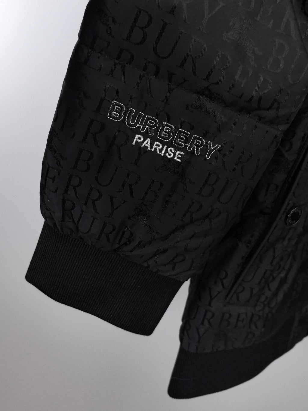 Long black puffer jacket sleeve hem with ribbed cuffs and logo embroidery