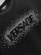 Close-up of rhinestone logo on the front of a black crewneck sweatshirt