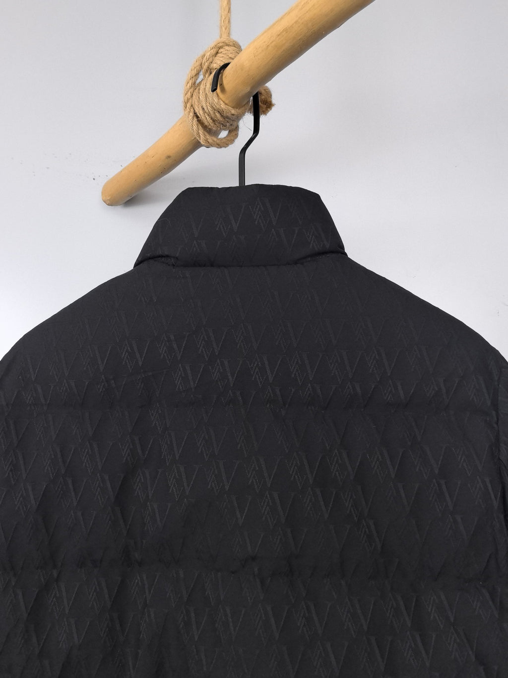 Black puffer jacket with allover monogram-style pattern on the back