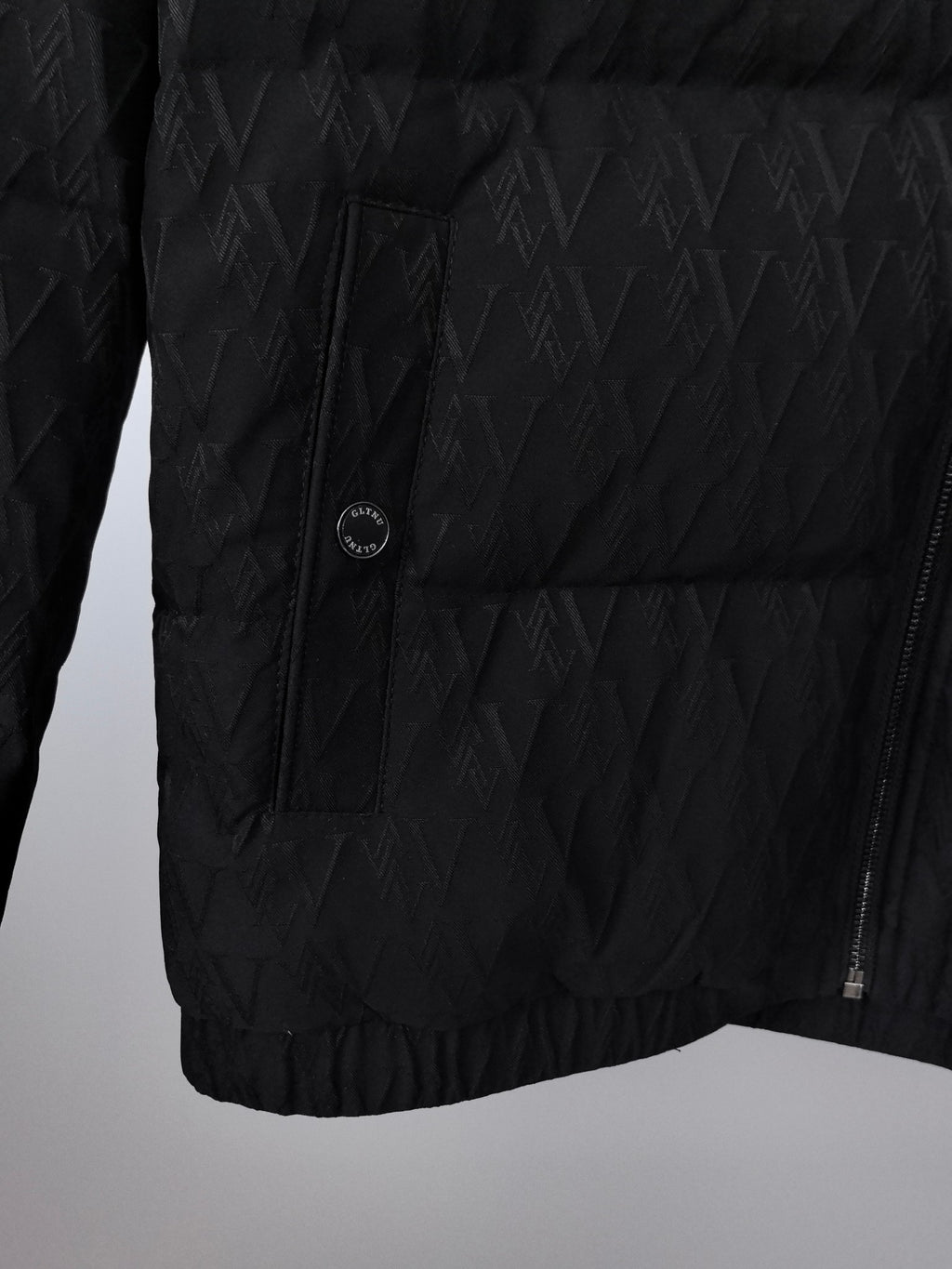 Black quilted puffer jacket front panel with circular logo patch