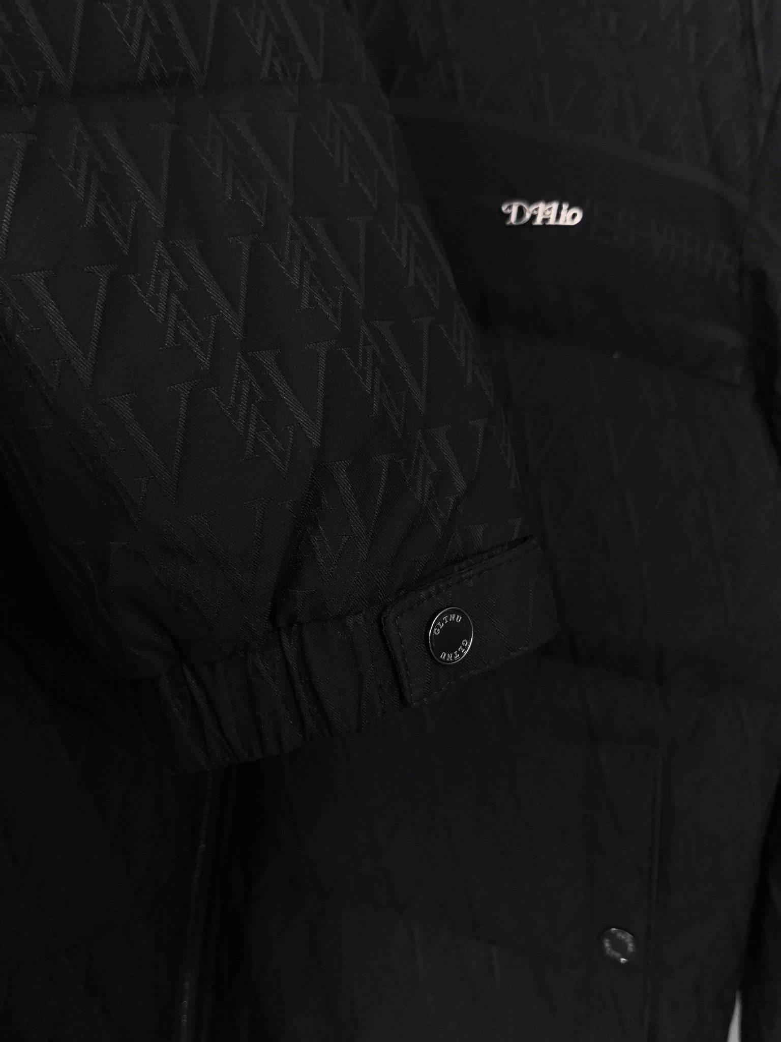 Black puffer jacket with monogram pattern and small chest logo