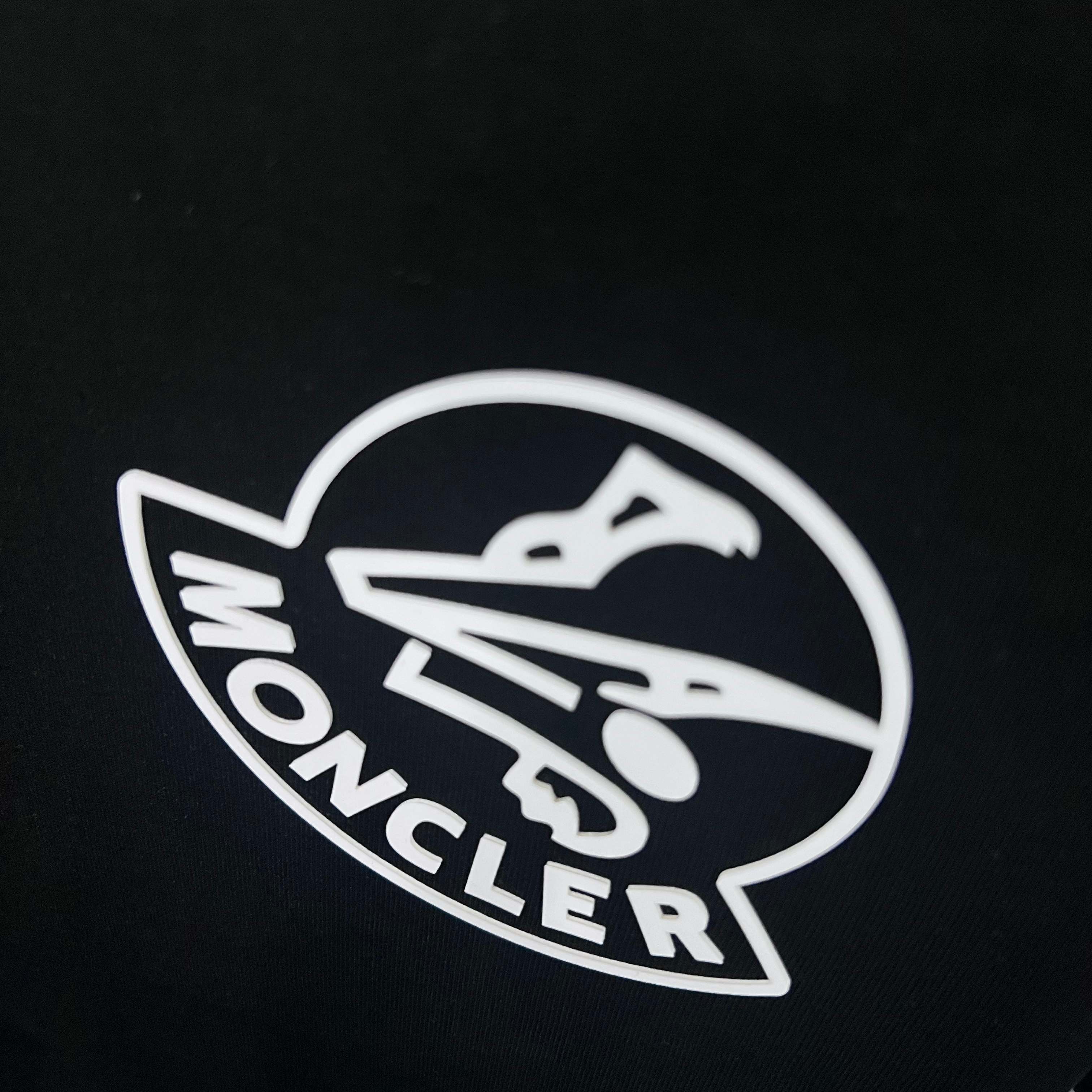 Moncler circular logo on black sweatshirt fabric close-up