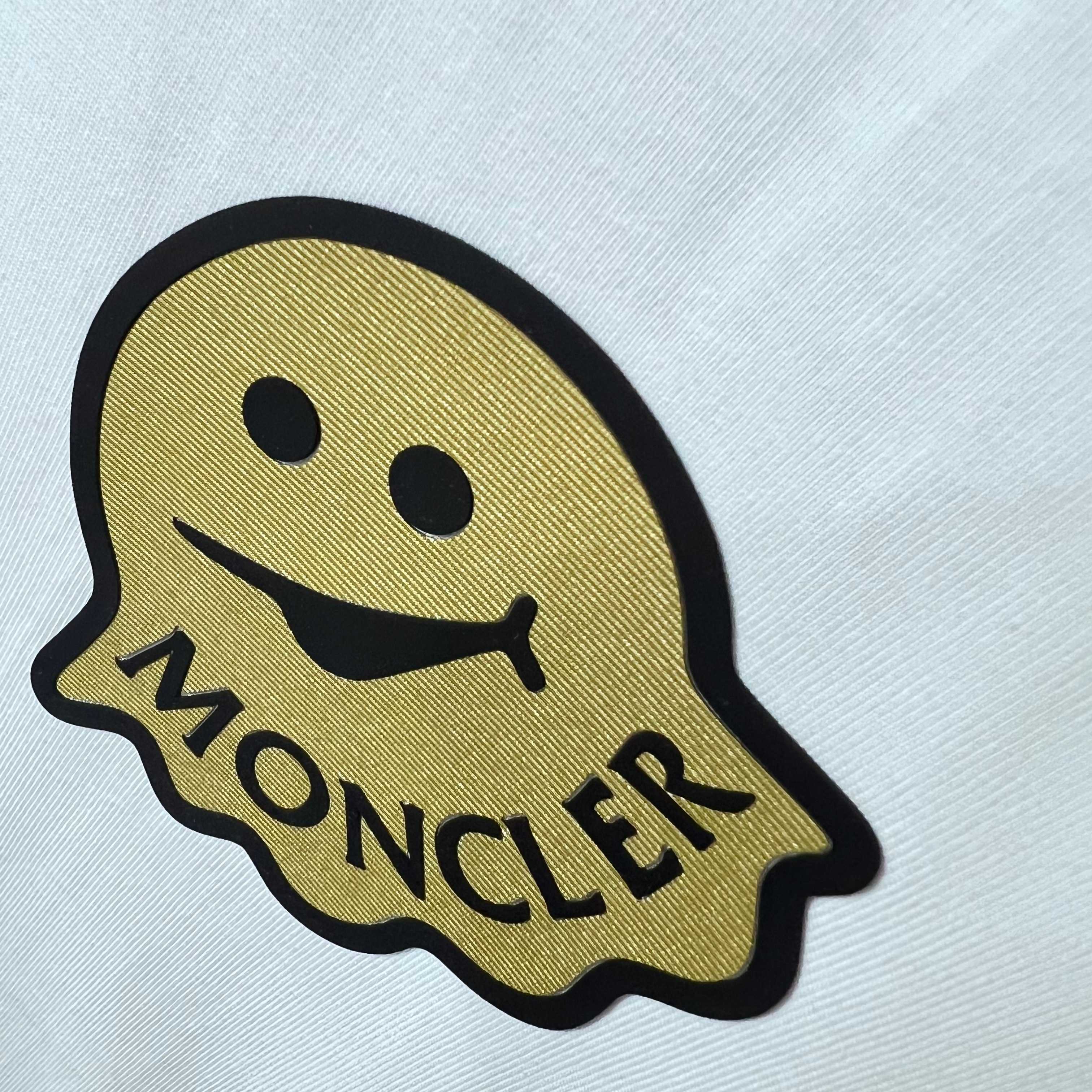 Moncler smiley face patch logo with MONCLER text on white fabric