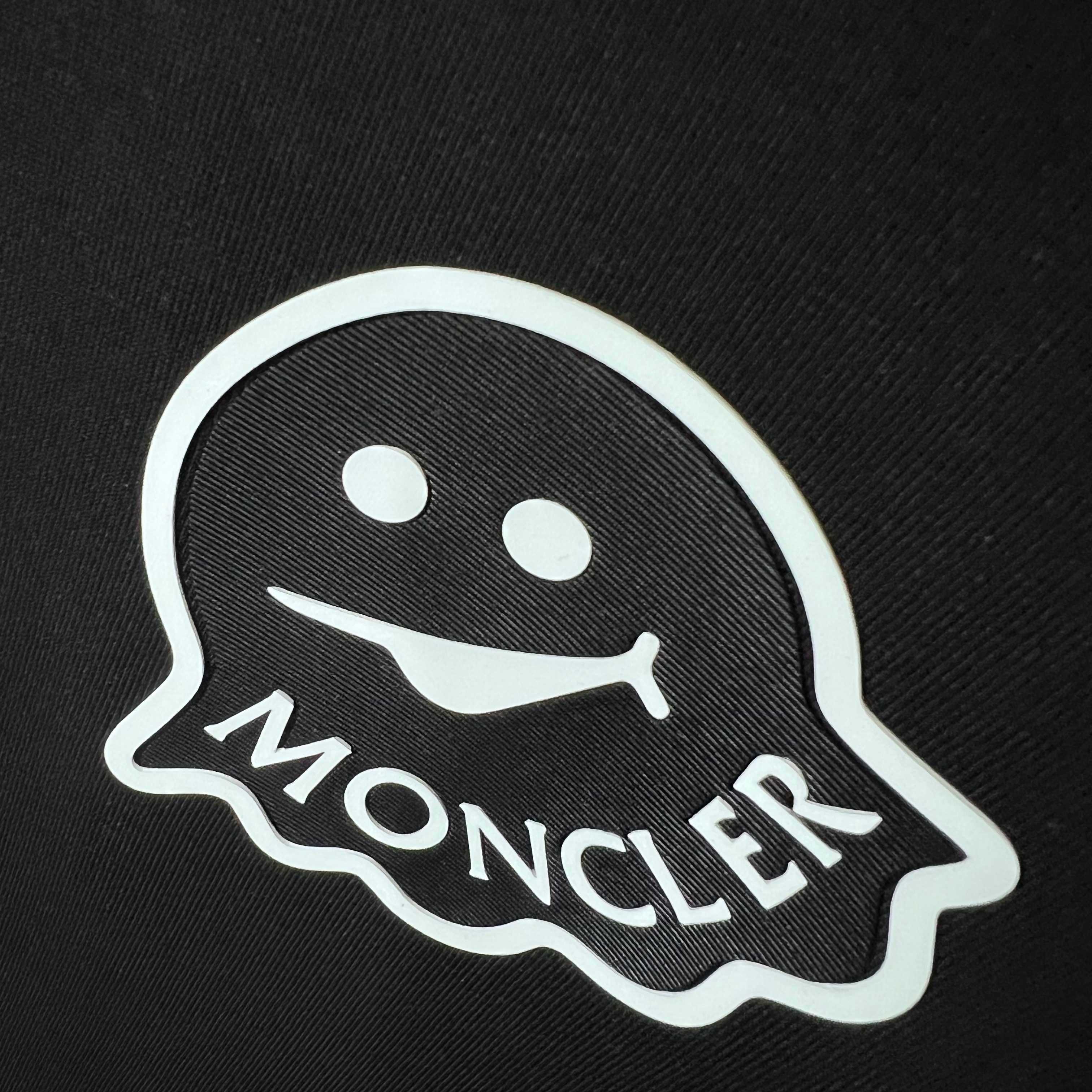 Moncler logo patch with white outline on dark fabric