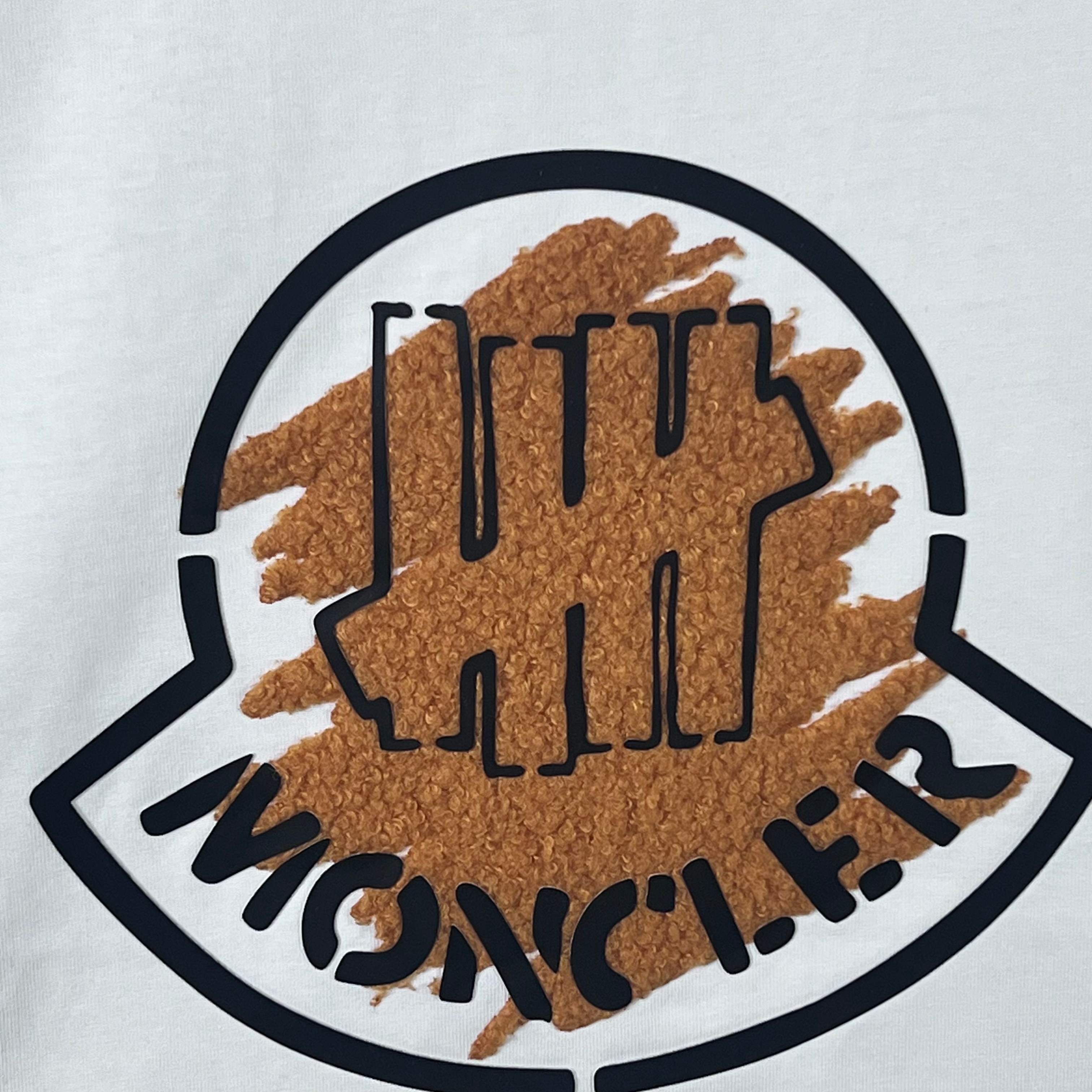Moncler logo patch on white sweatshirt with brown textured print and black outline